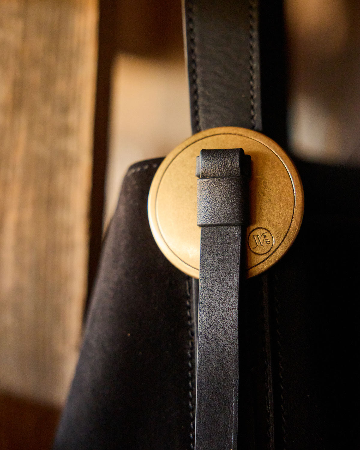 Close-up of a black leather strap with a wooden buckle on a blurred background