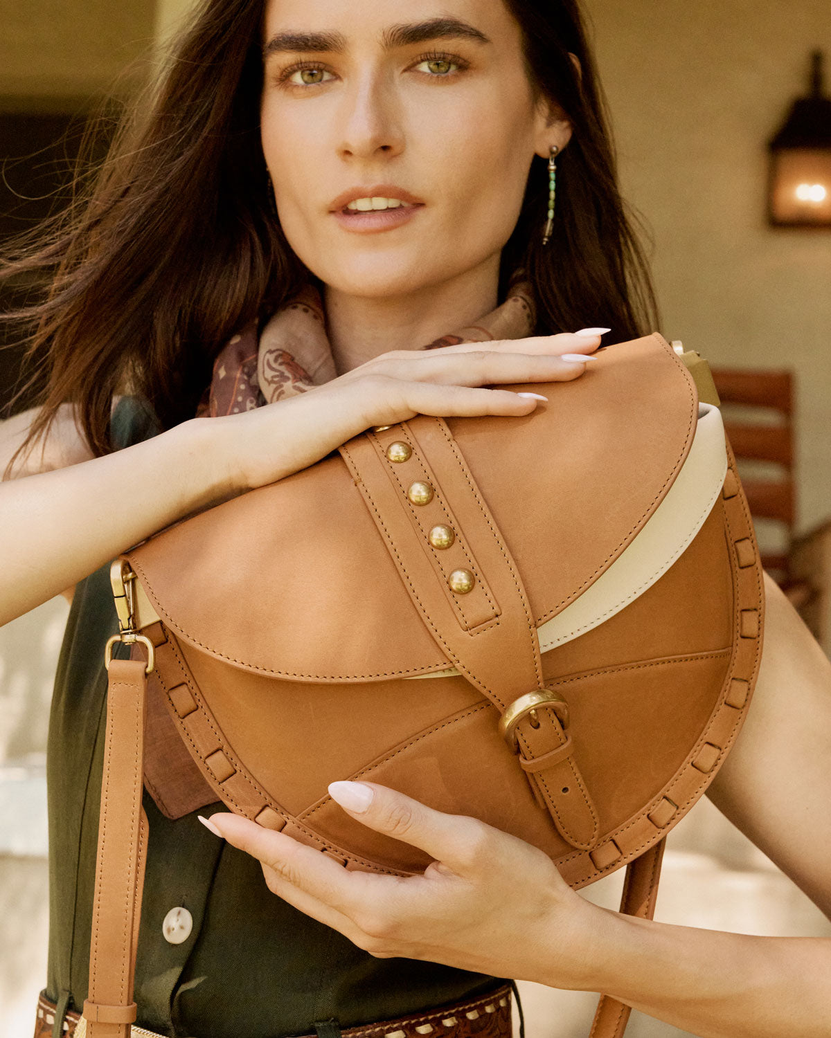 Woman holding a brown leather bag with gold accents