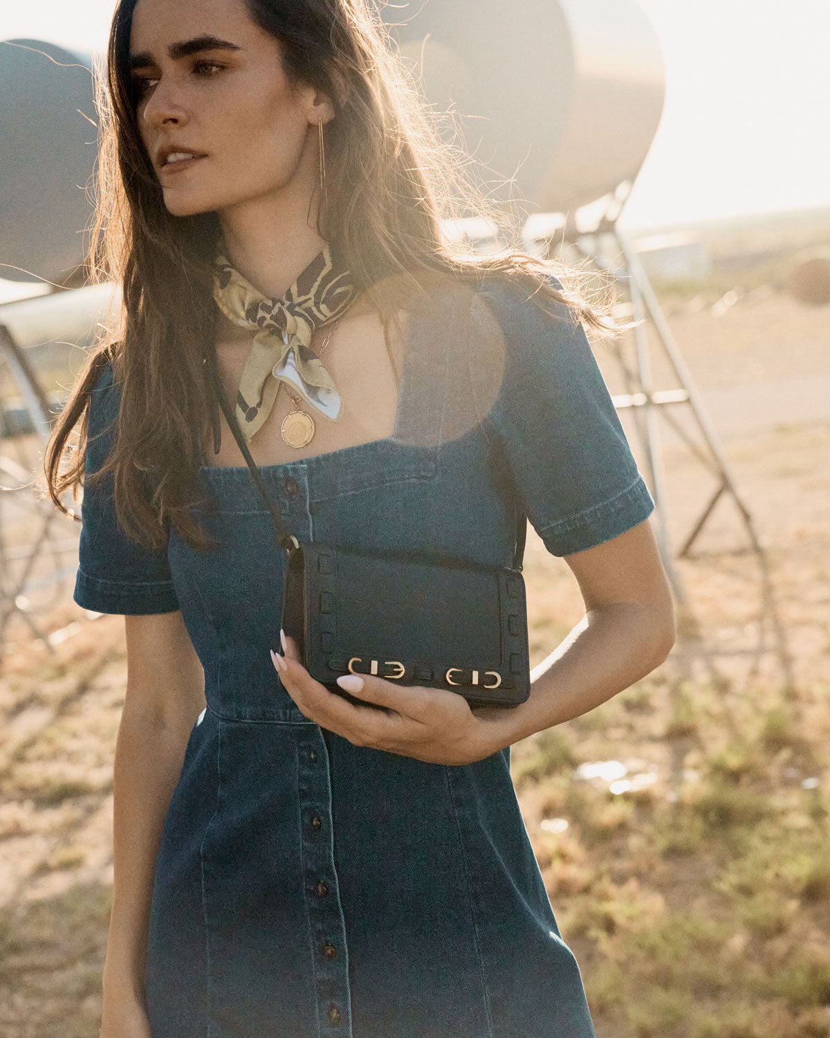 Woman holding a black handbag in an outdoor setting