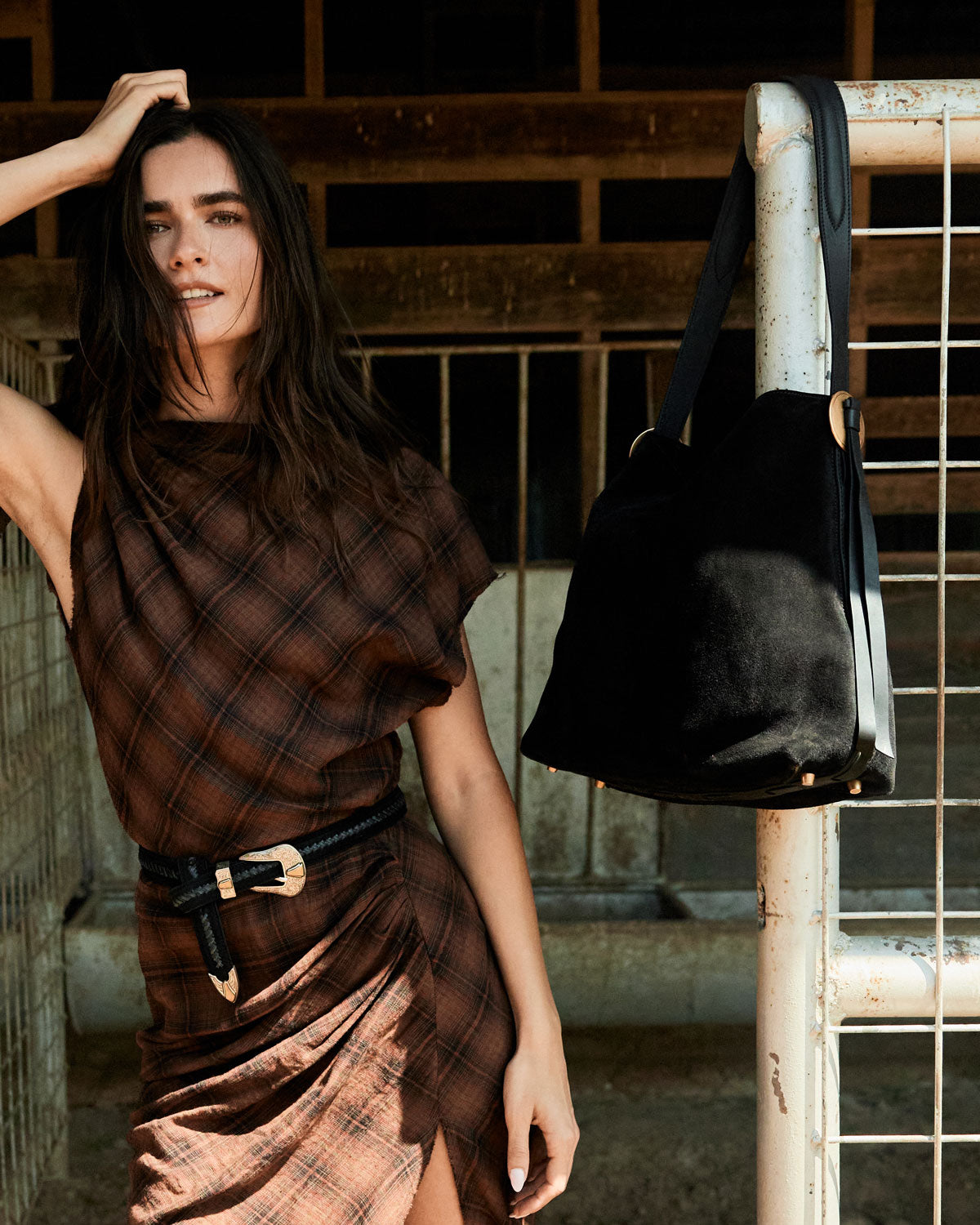 Woman in a plaid dress holding a black bag in an industrial setting