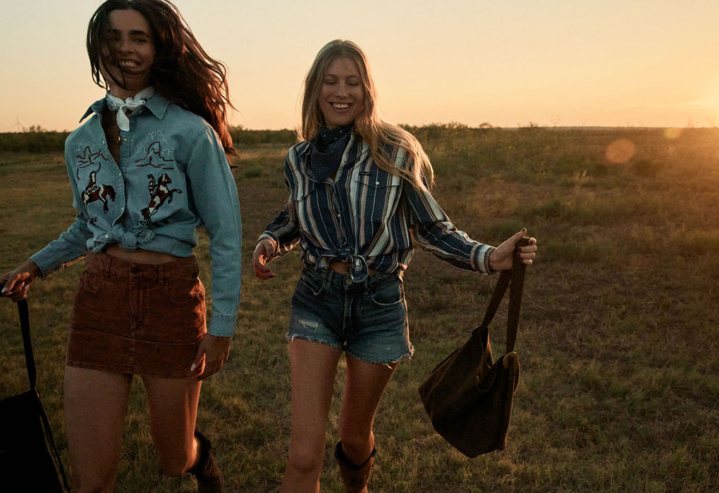 Two women walking together in a field at sunset.