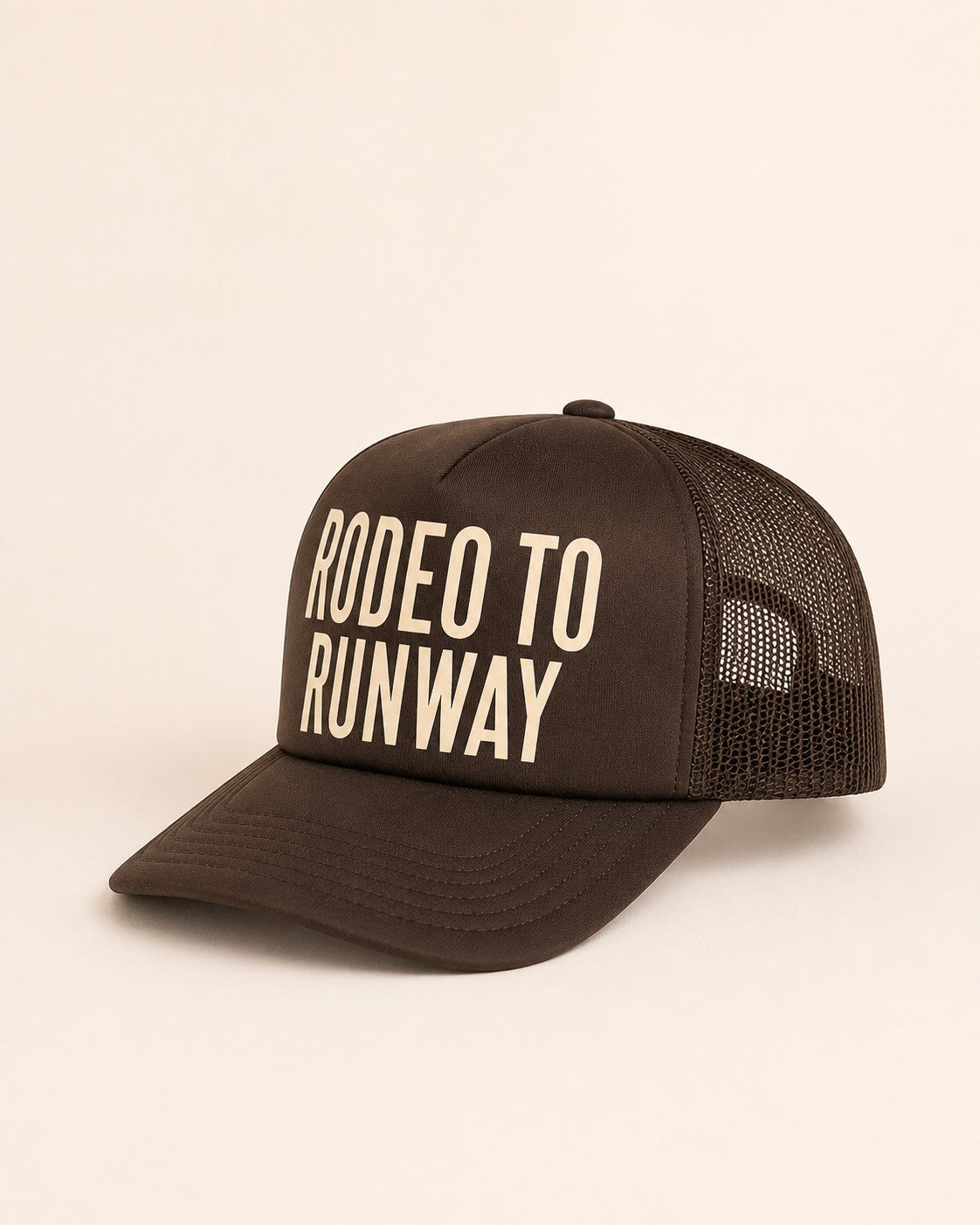 Brown trucker cap with 'Rodeo to Runway' text on a light background