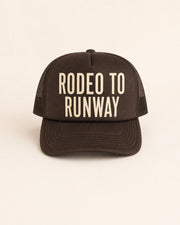 Brown trucker hat with 'Rodeo to Runway' text on a light background