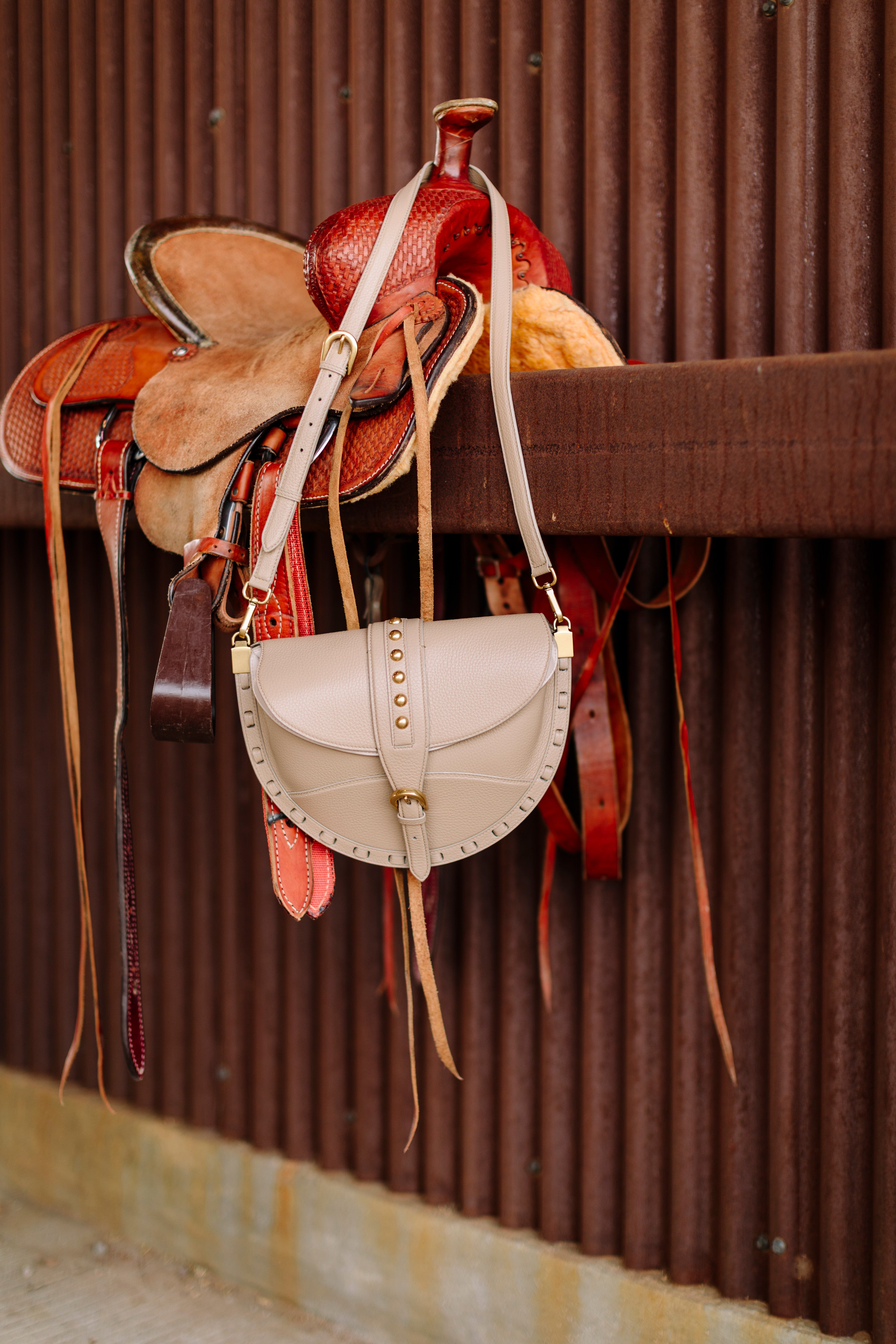 Saddle and leather bag hanging on a corrugated metal wall