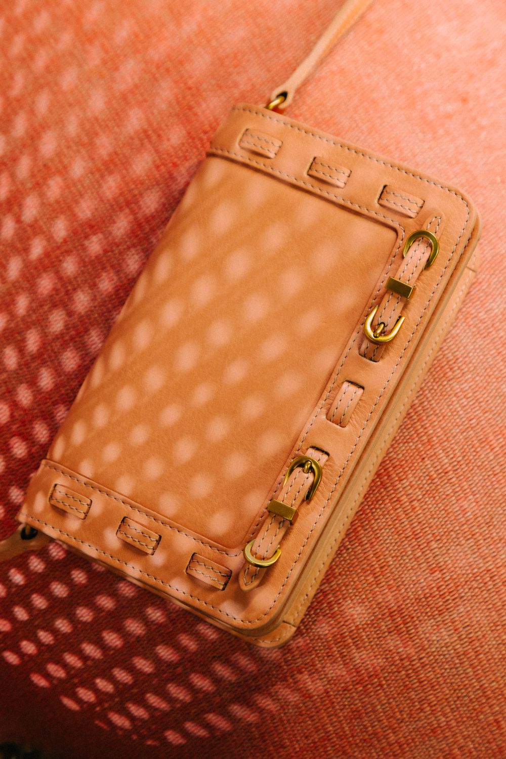Close-up of a pink leather bag with a brass hardware