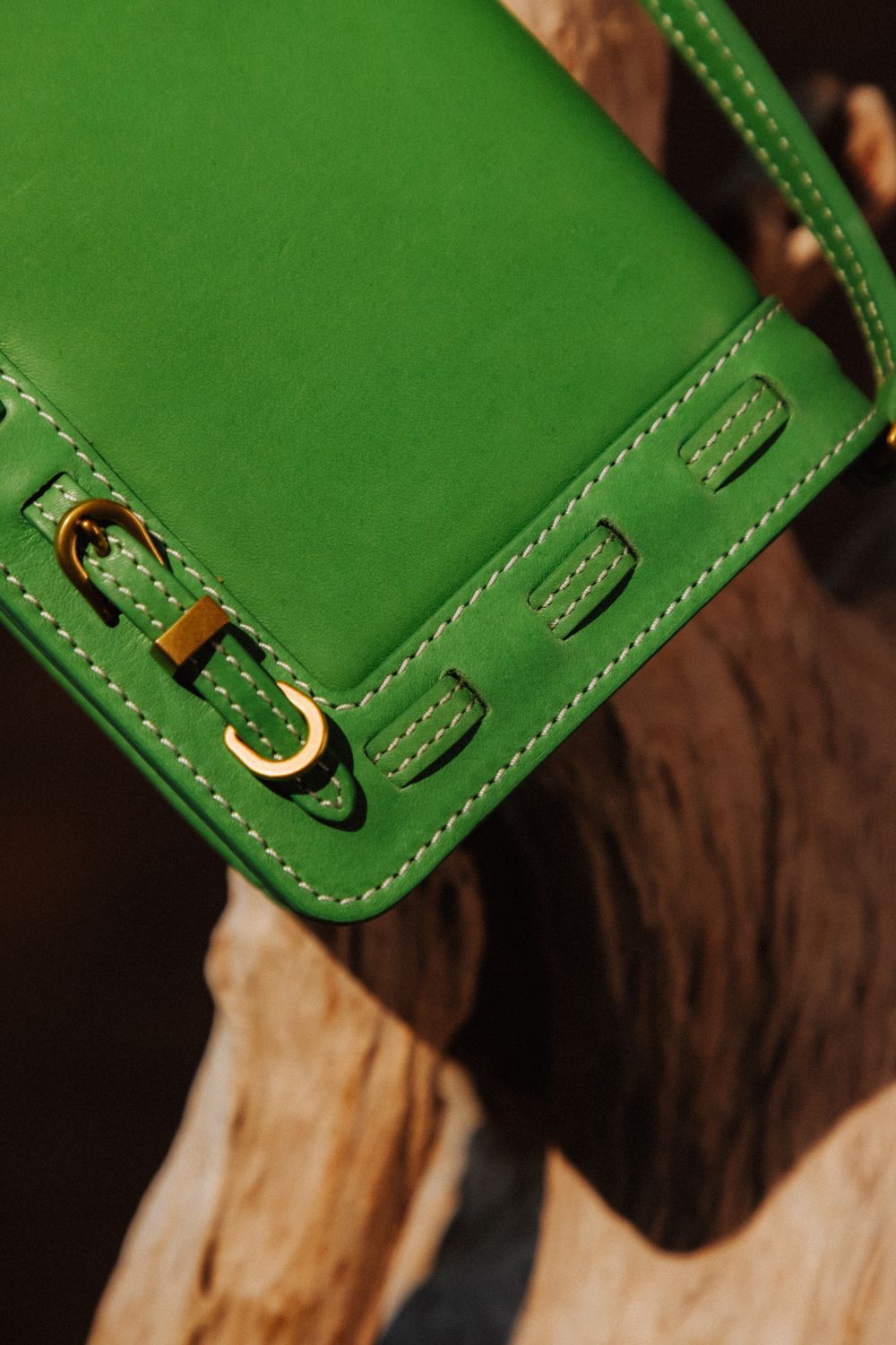Close-up of green leather with brass stitching and a button