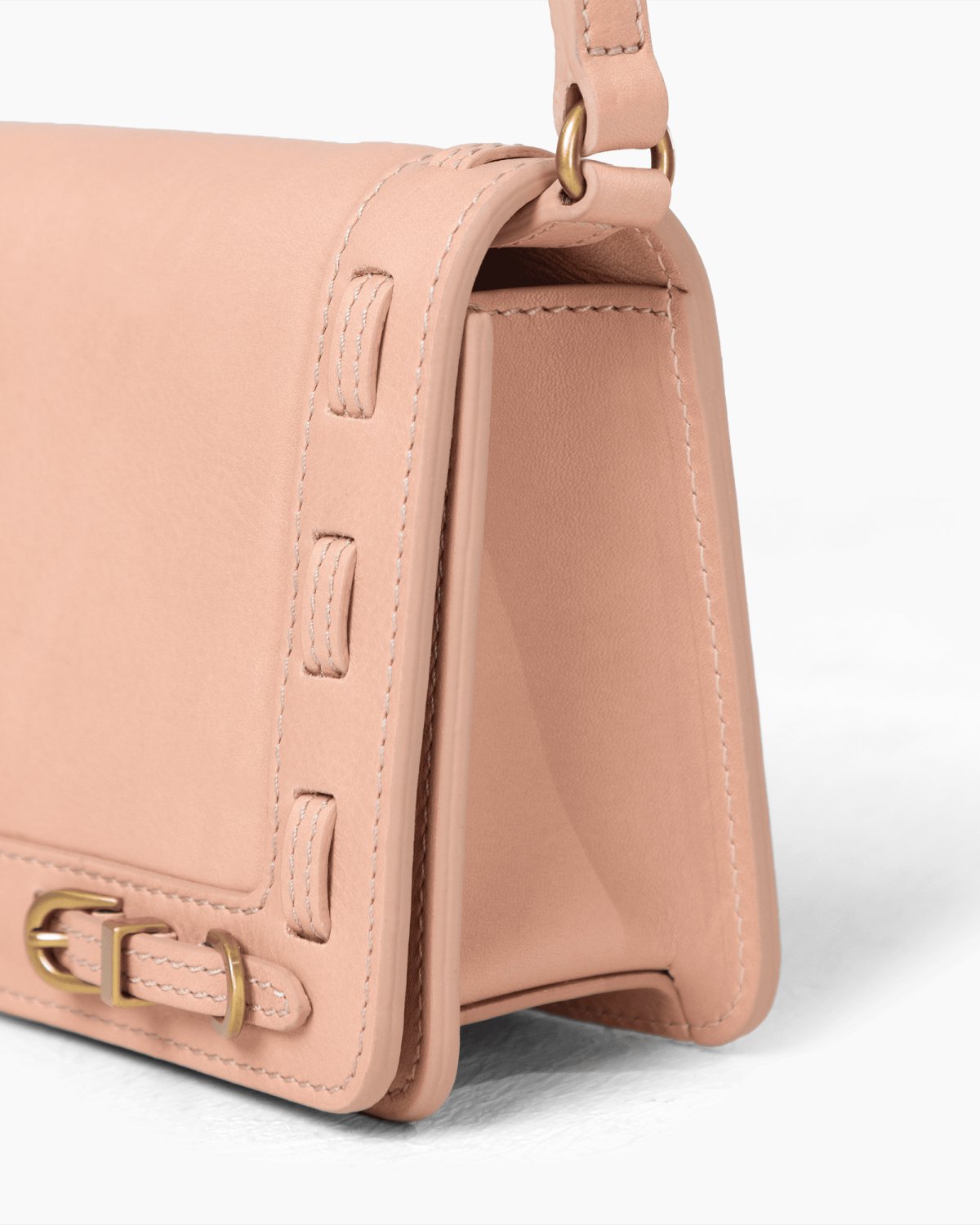 Close-up of a pink handbag with brass accents on a white background