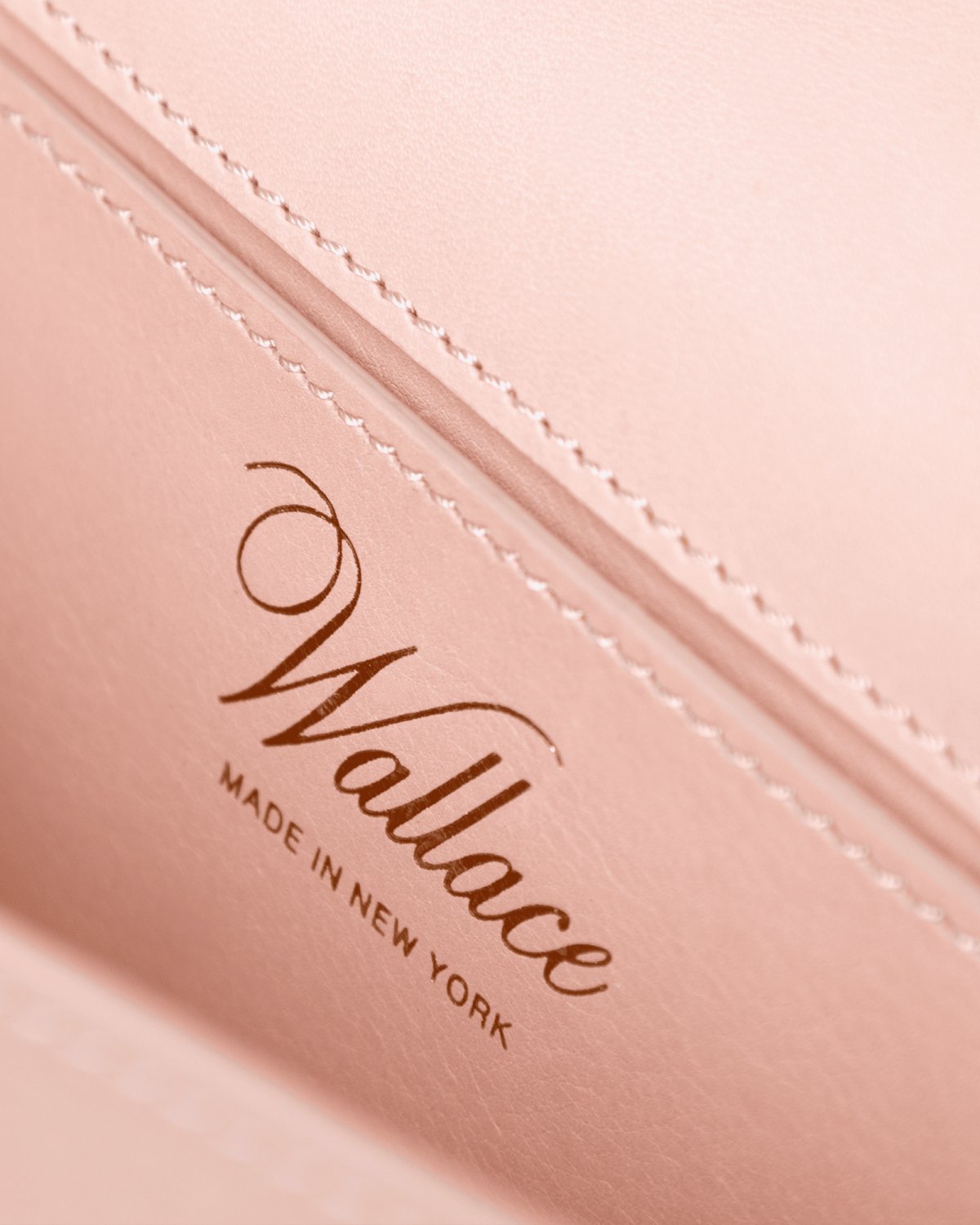 Close-up of a pink leather product with 'Wallace Made in New York' printed in gold