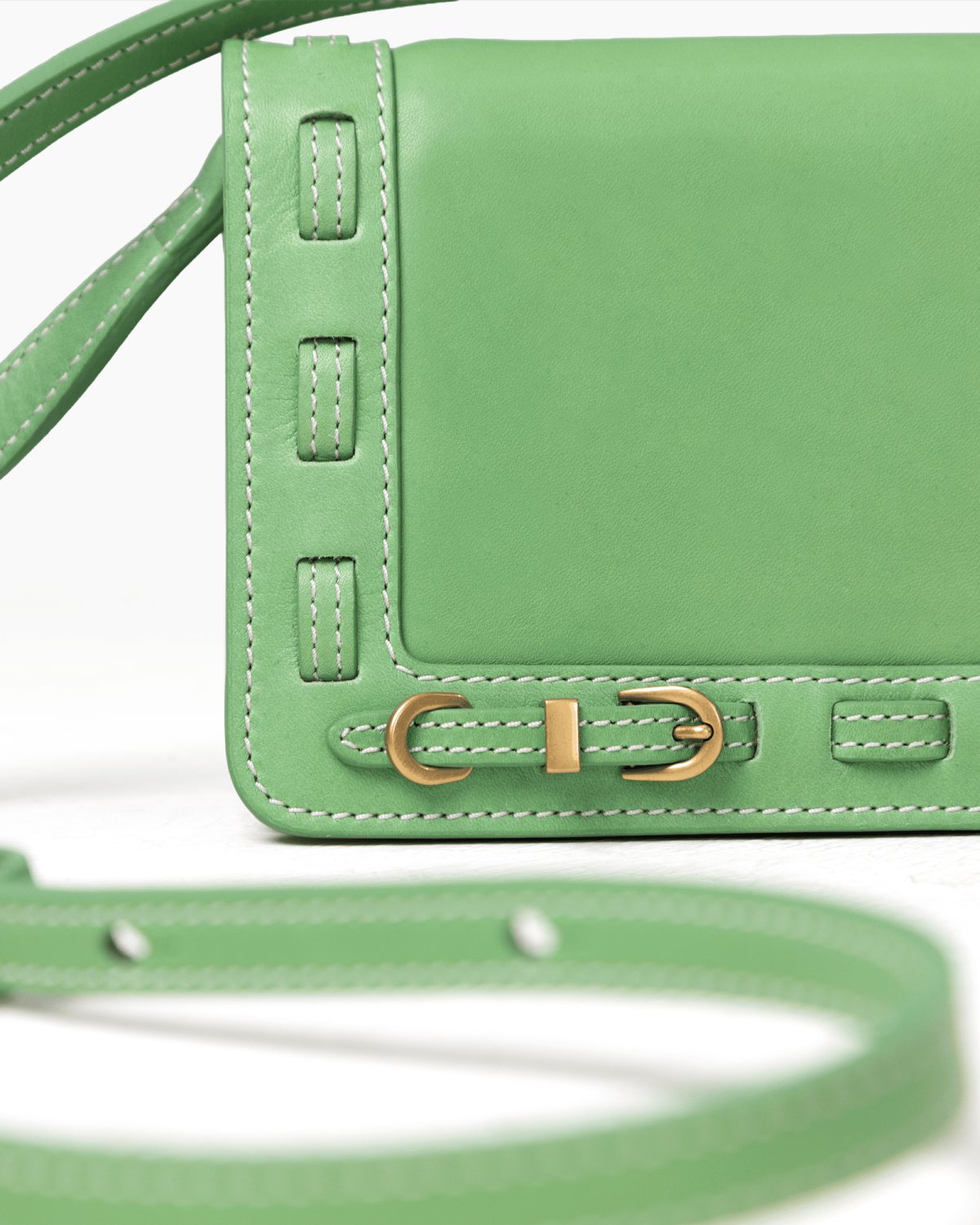 Green handbag with brass accents on a white background