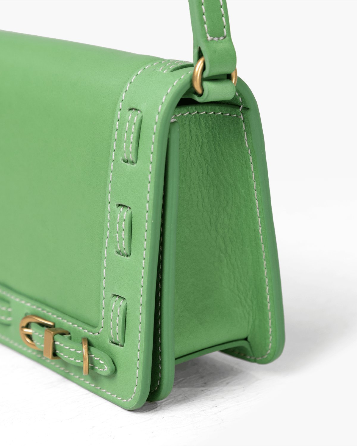 Green handbag with brass accents on a white background