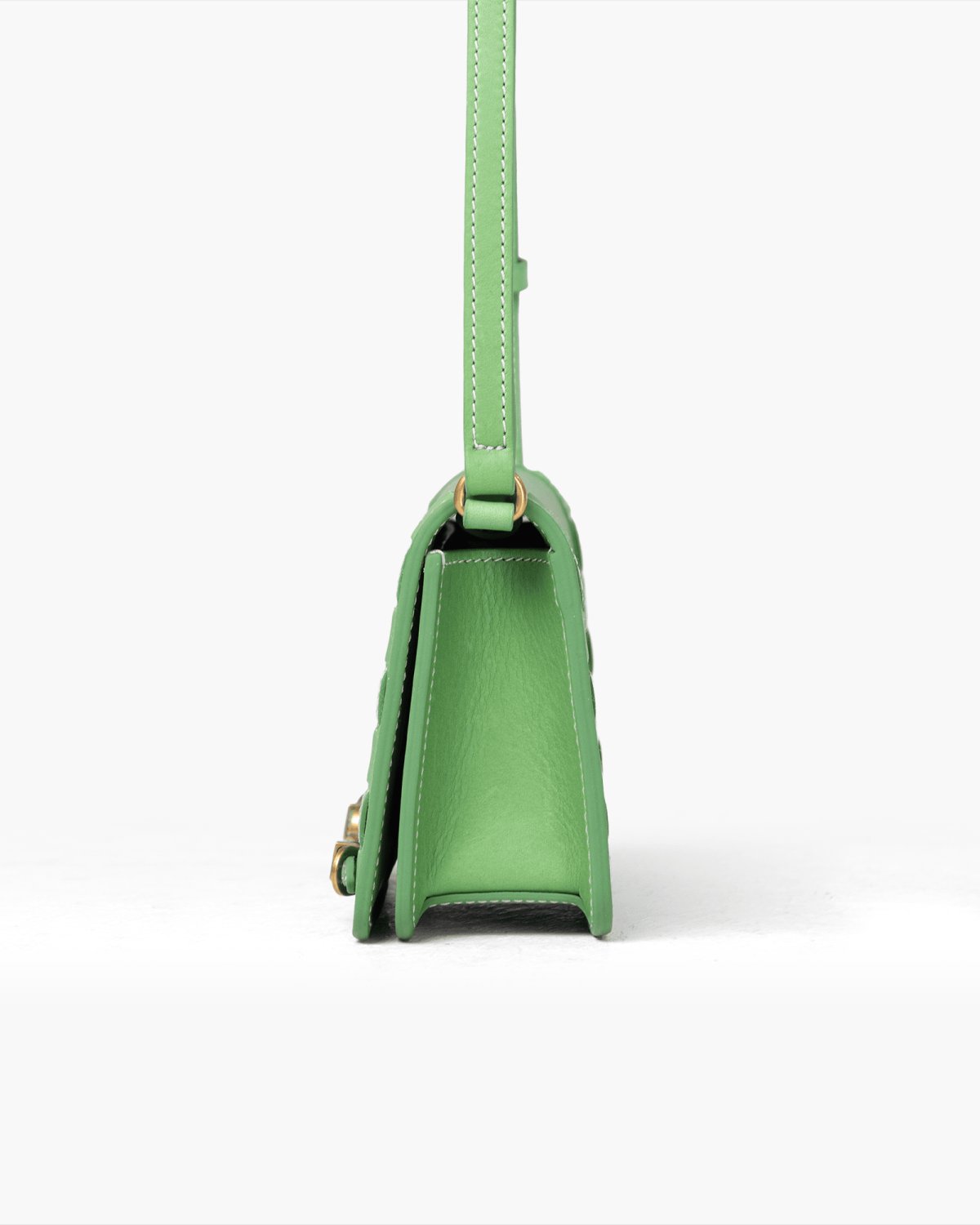 Green leather handbag with a strap on a white background