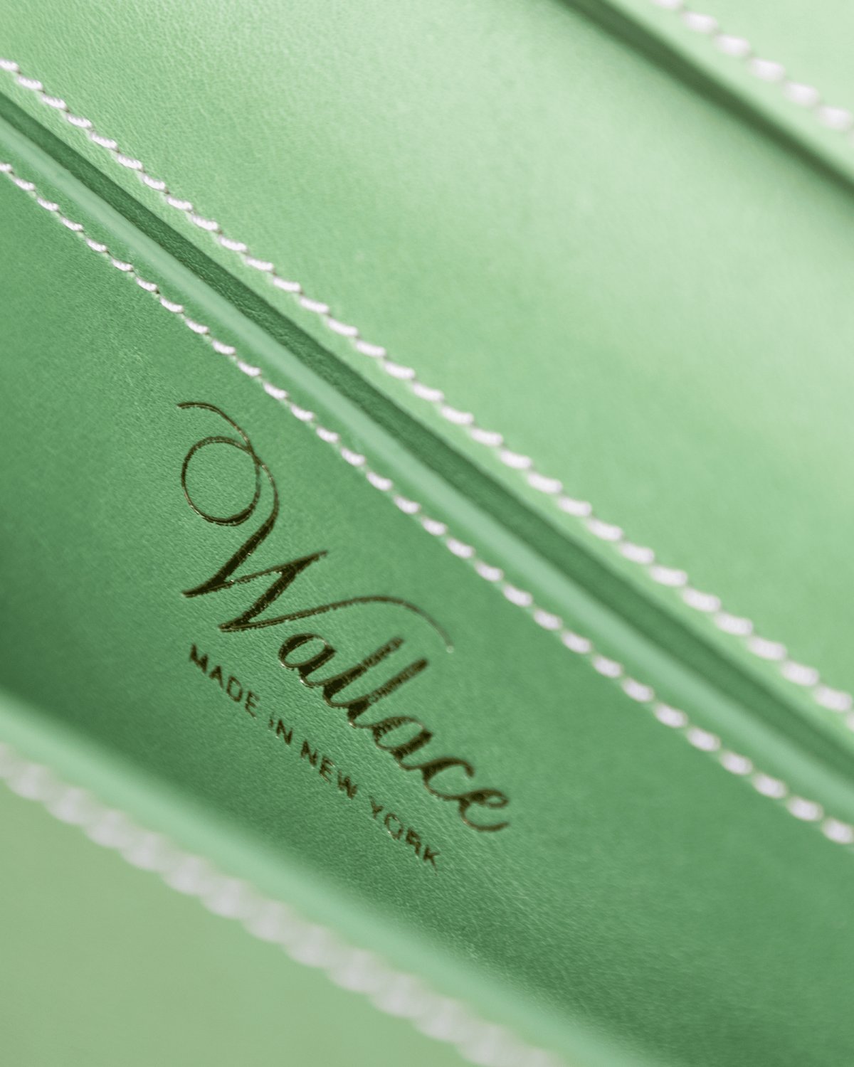 Close-up of a green leather product with 'Wallace Made in New York' branding.