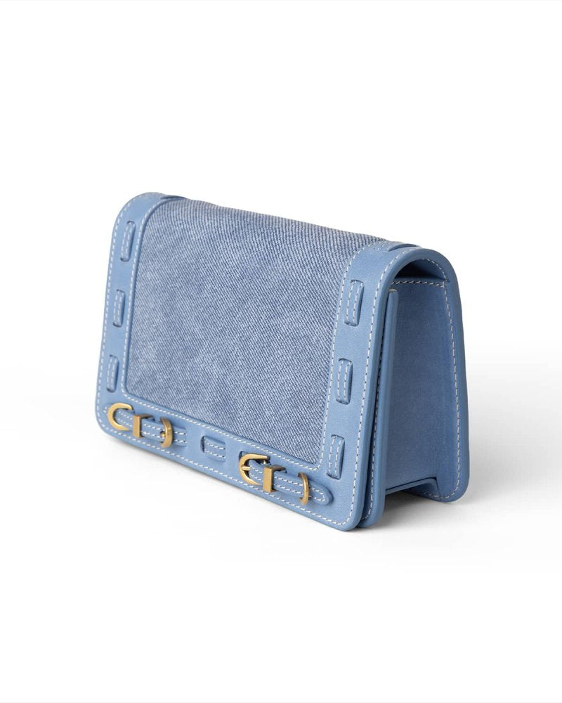 Blue handbag with brass hardware on a white background