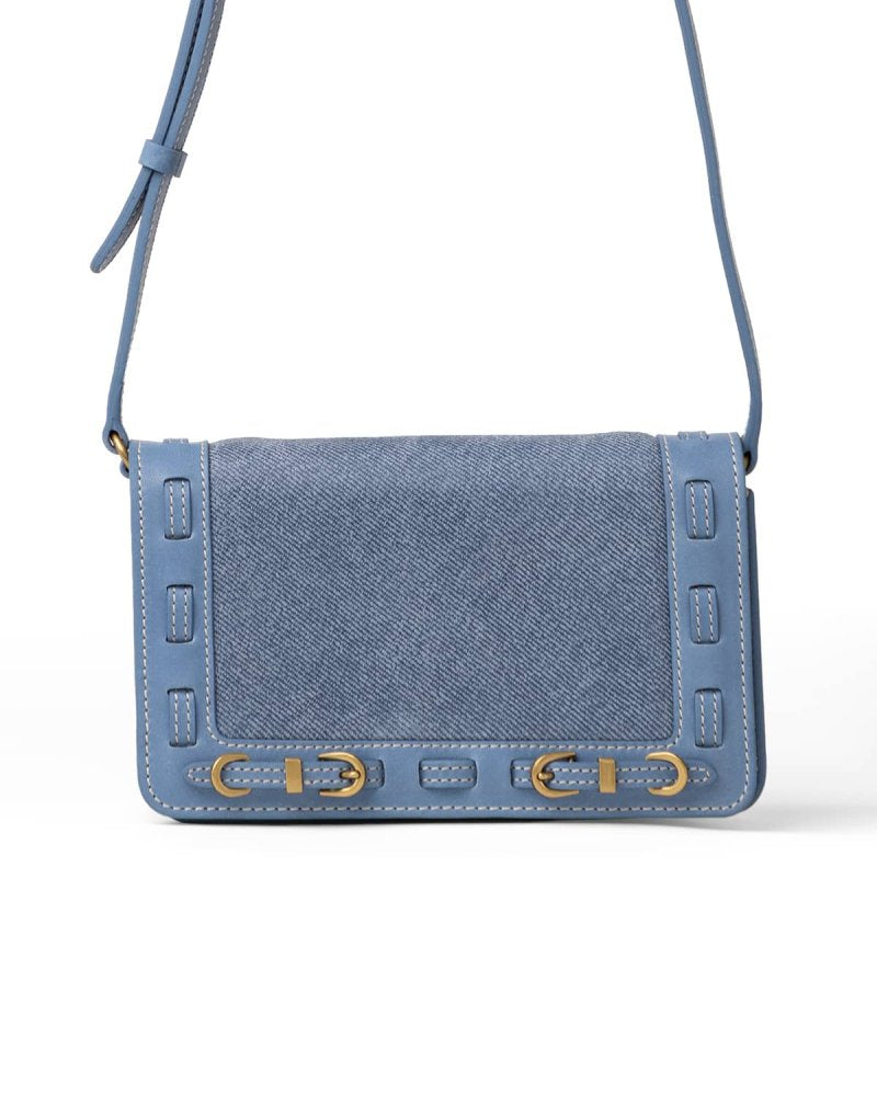 Blue denim handbag with brass accents on a white background