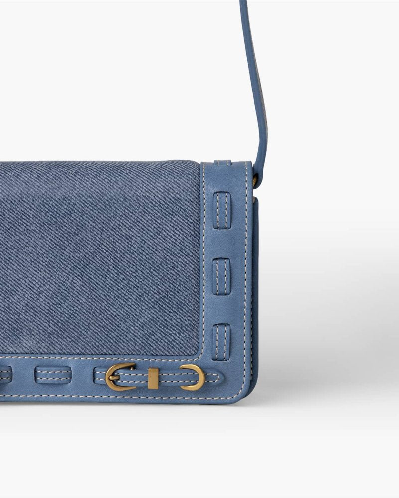 Blue denim handbag with brass hardware on a white background