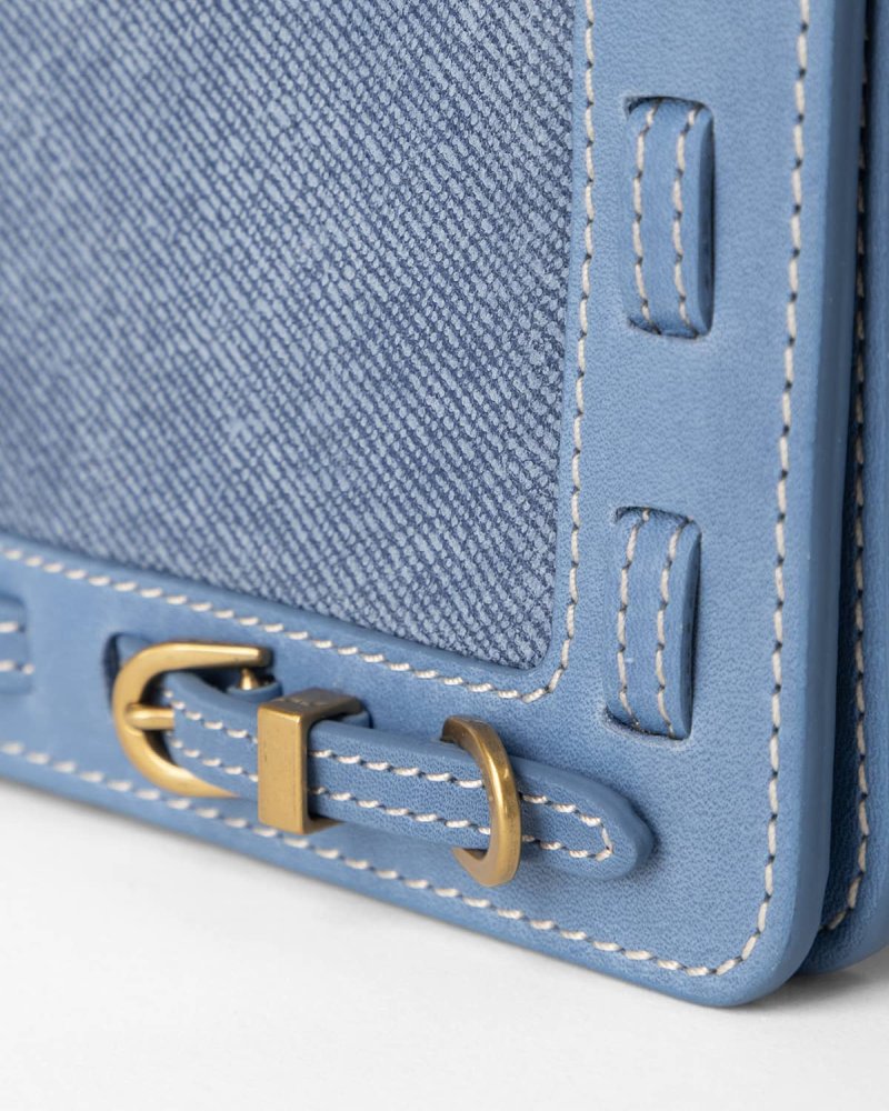 Close up of Denim blue handbag with brass hardware