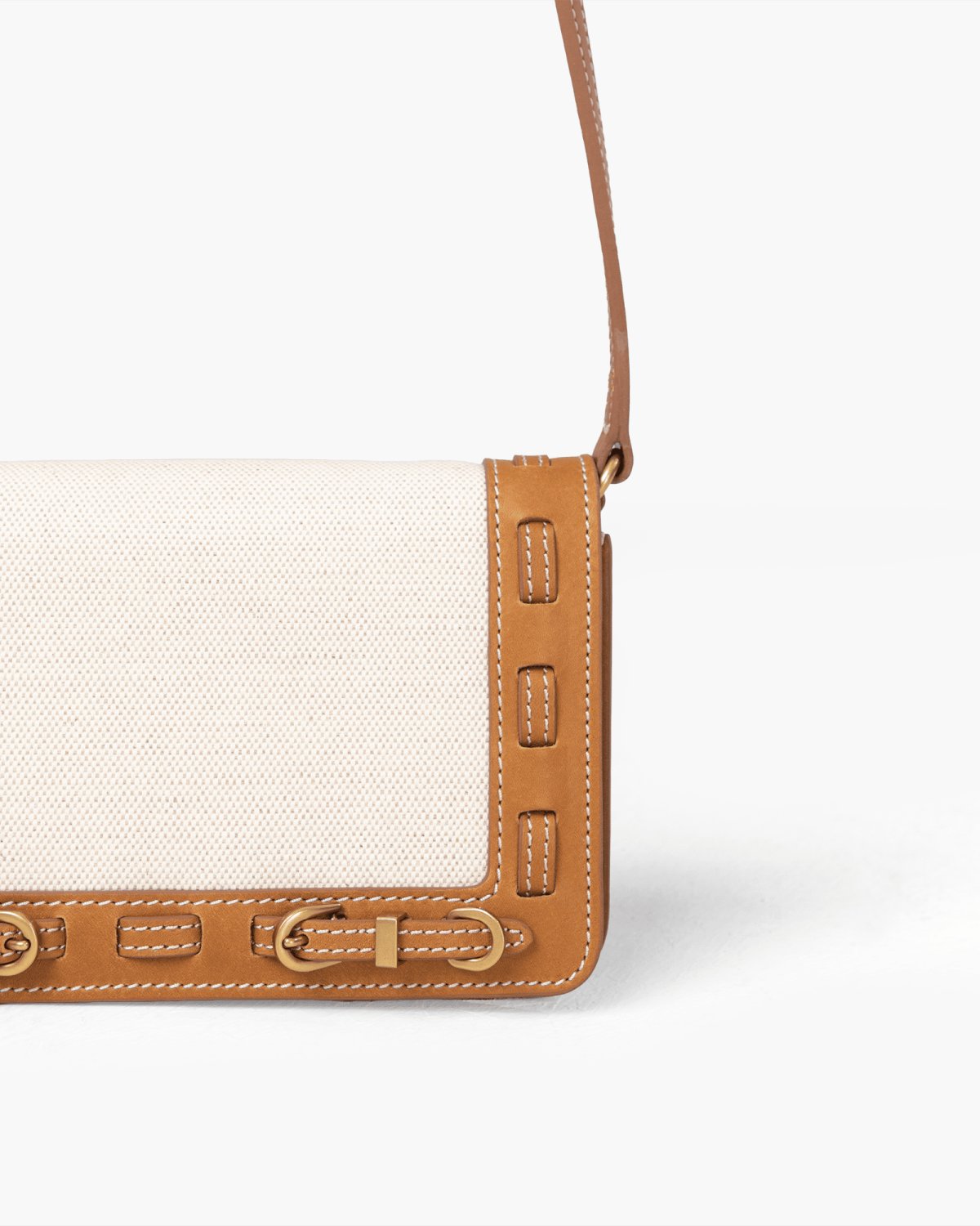 Close-up of a handbag with light linen panel, brown leather accents on a white background