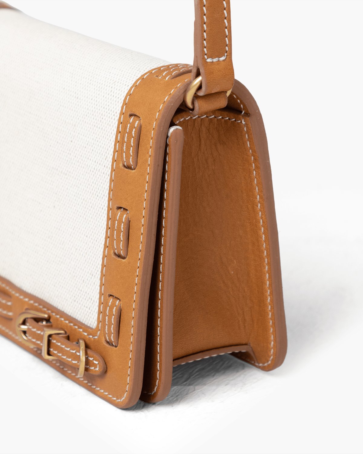 Close-up of a brown leather handbag with light linen panel on a white background