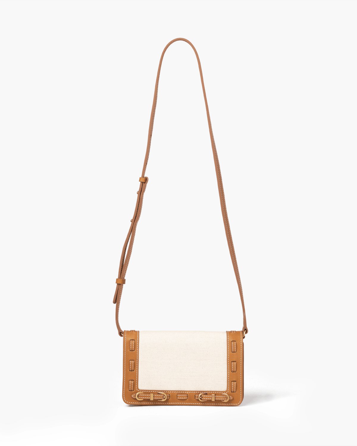 Crossbody bag with light linen panel front panel and brown leather strap on a light gray background