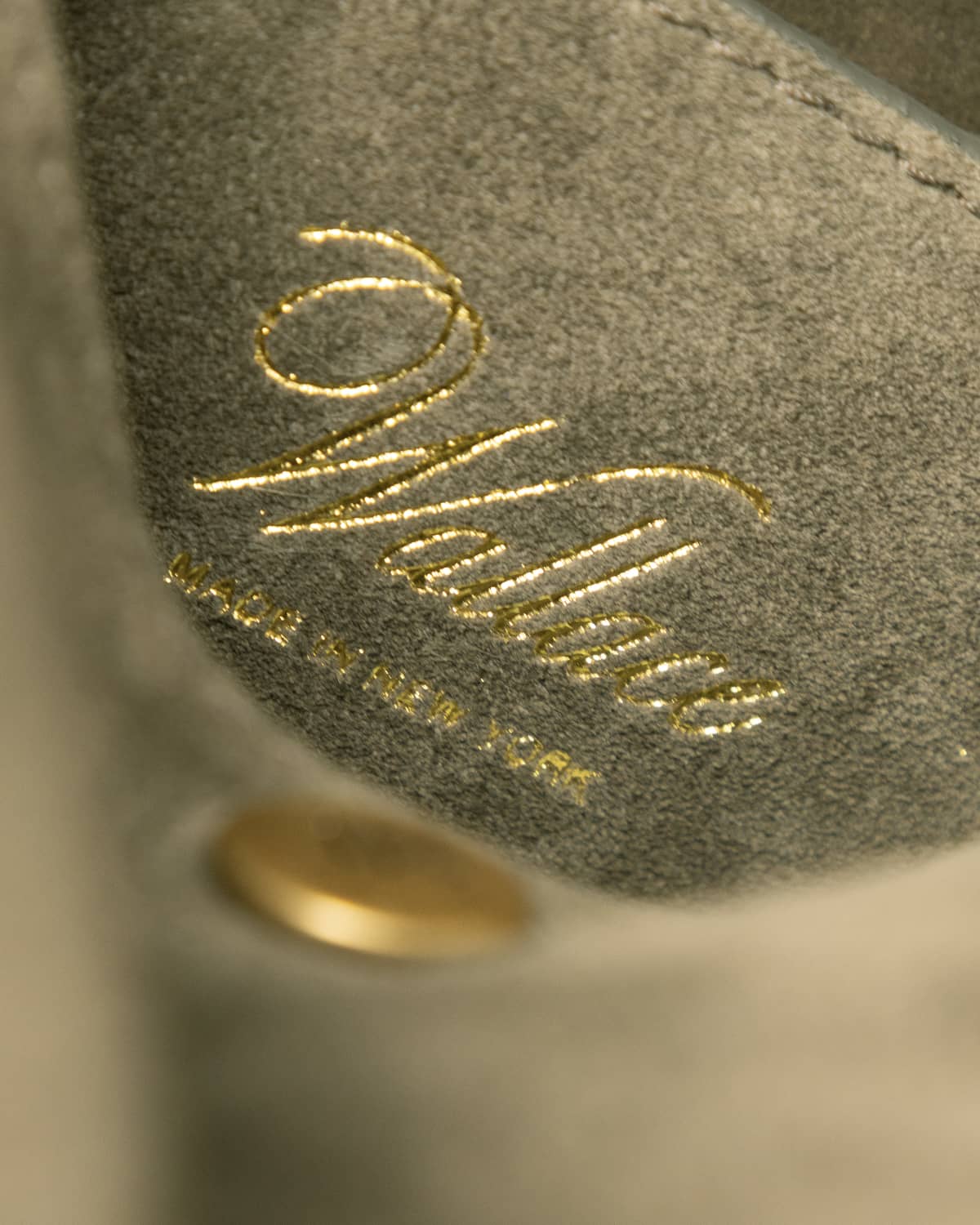 Close up of script Wallace logo in gold on olive leather