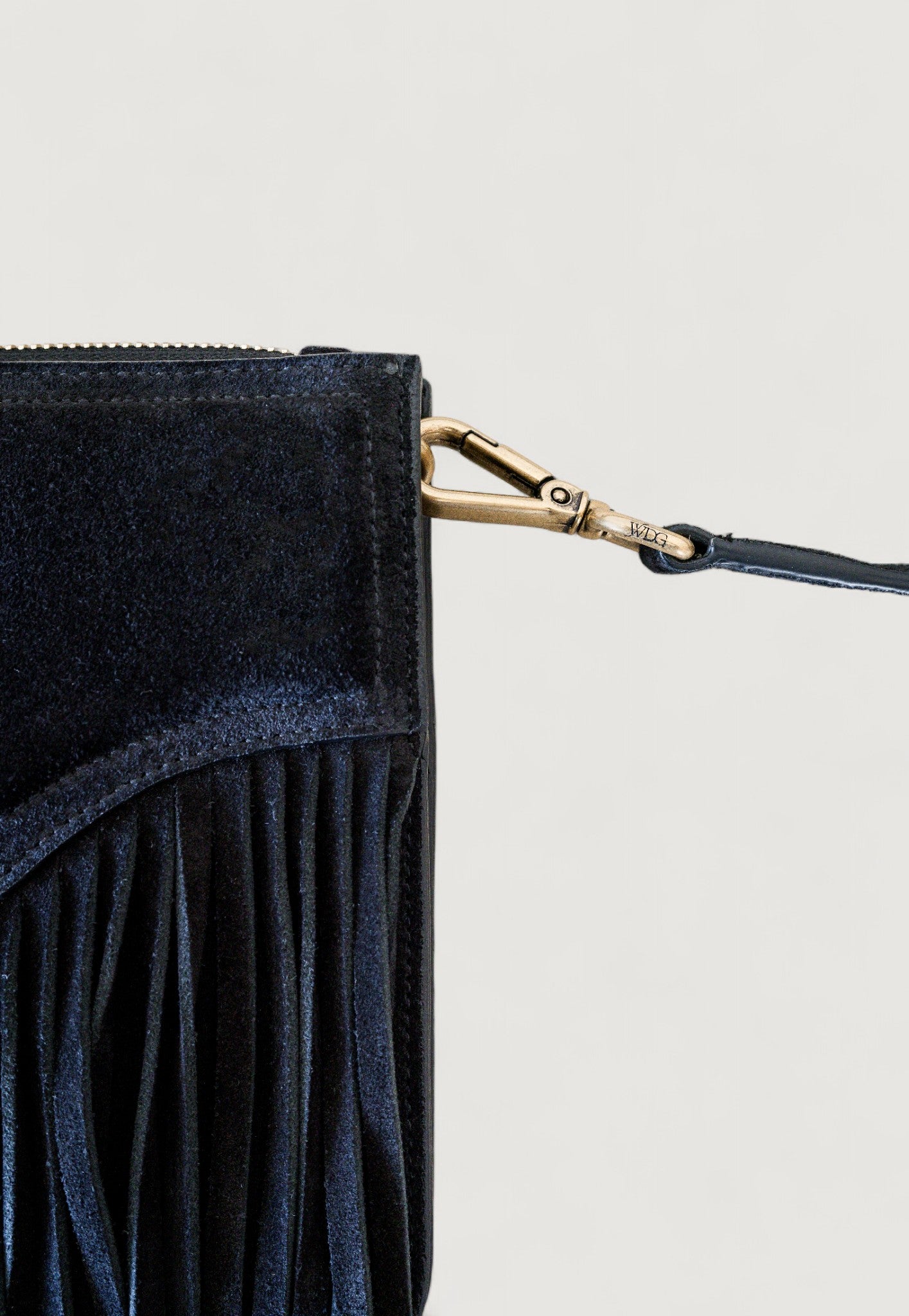 Black suede clutch with branded brass clasp on a light gray background