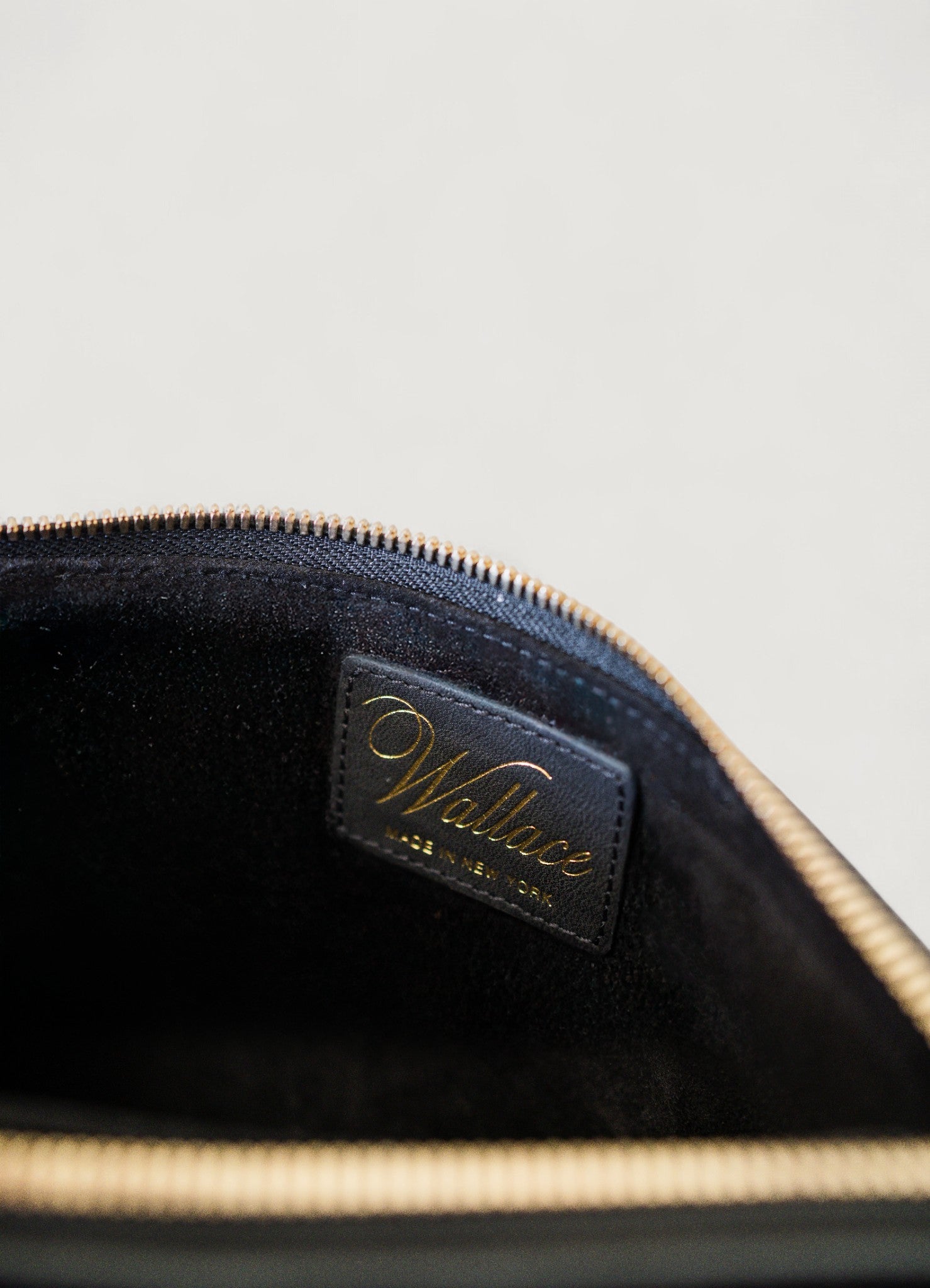 Close-up of a black leather pouch with 'Wallace' branding on a light gray background