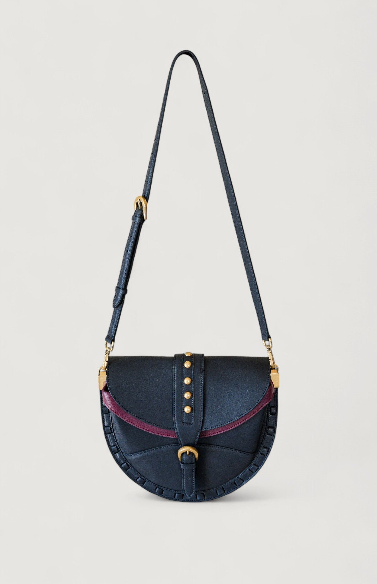 Black handbag with brass accents on a light gray background