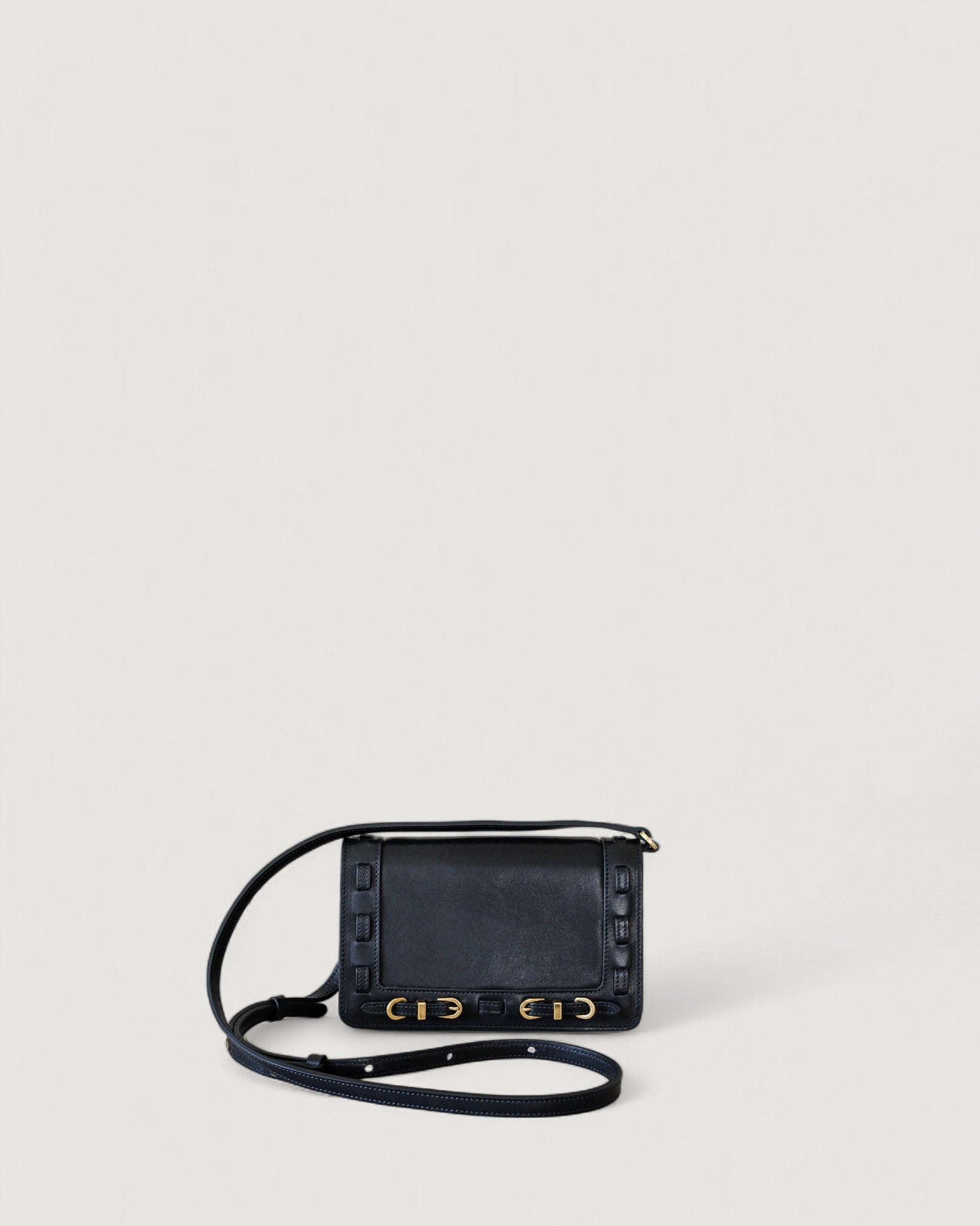 Black handbag with brass accents on a light gray background