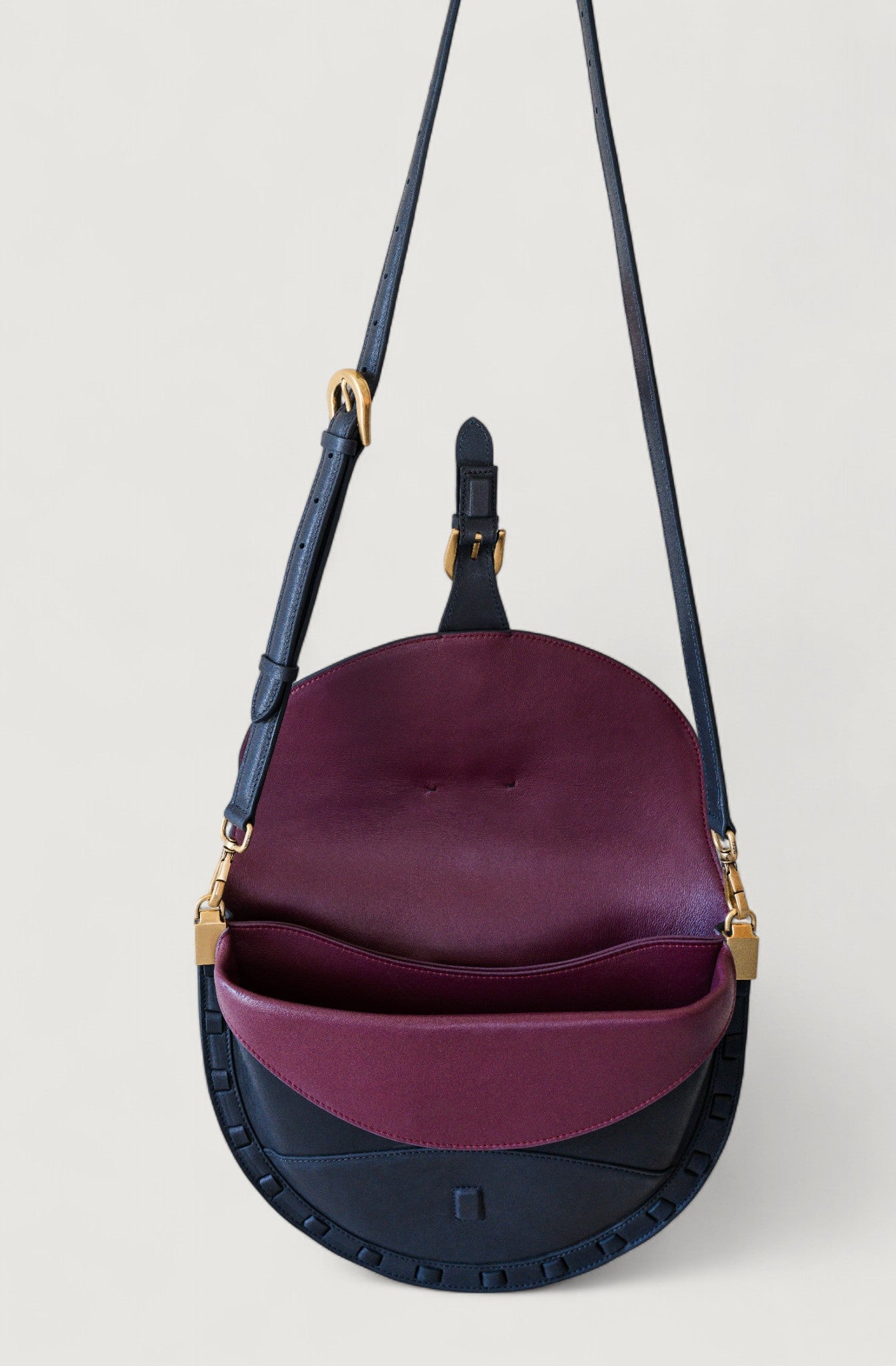 Two-toned handbag with burgundy top section and black bottom section on a light gray background