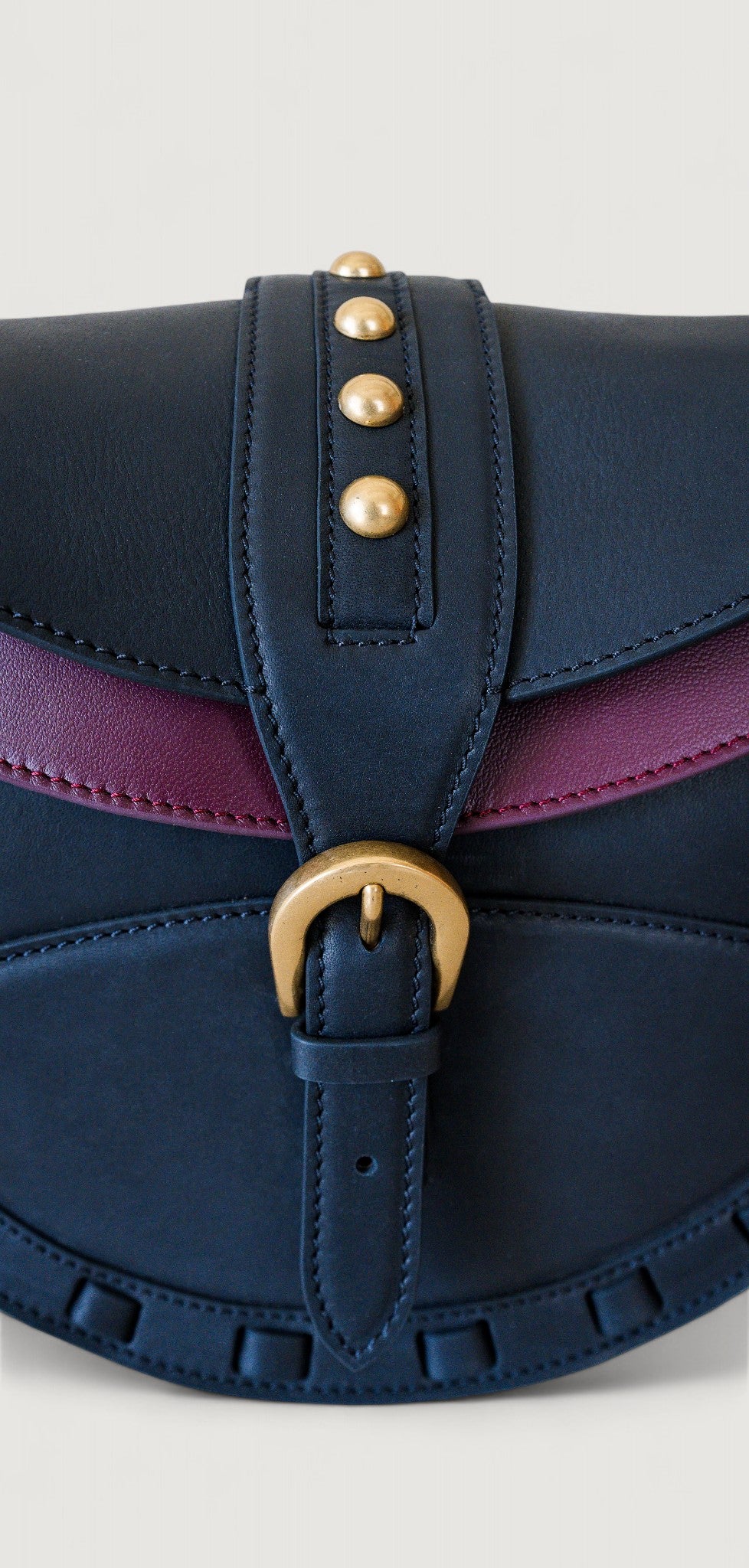 Black handbag with brass hardware on a light gray background