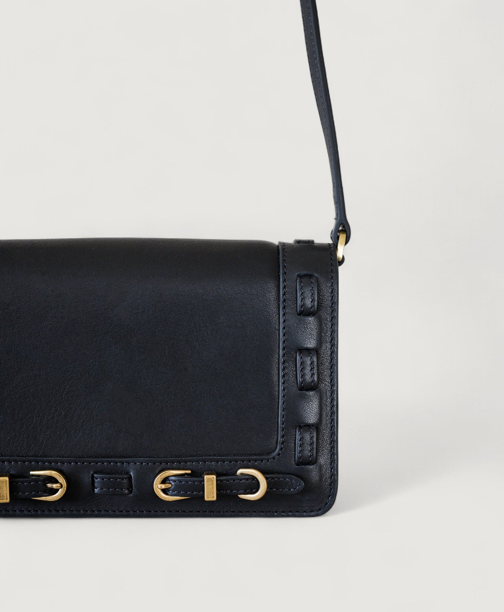 Black handbag with brass accents on a light gray background