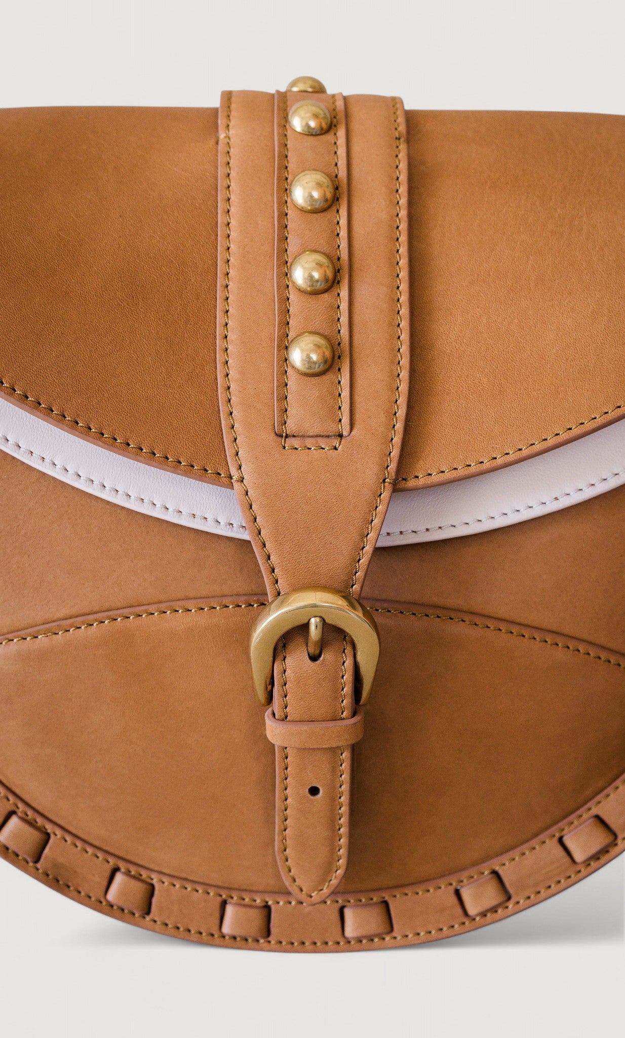 Brown leather saddle bag with brass accents on a light gray background