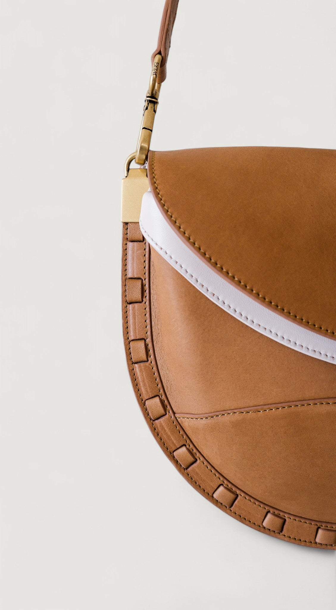 Brown leather handbag with nude interior on a light gray background