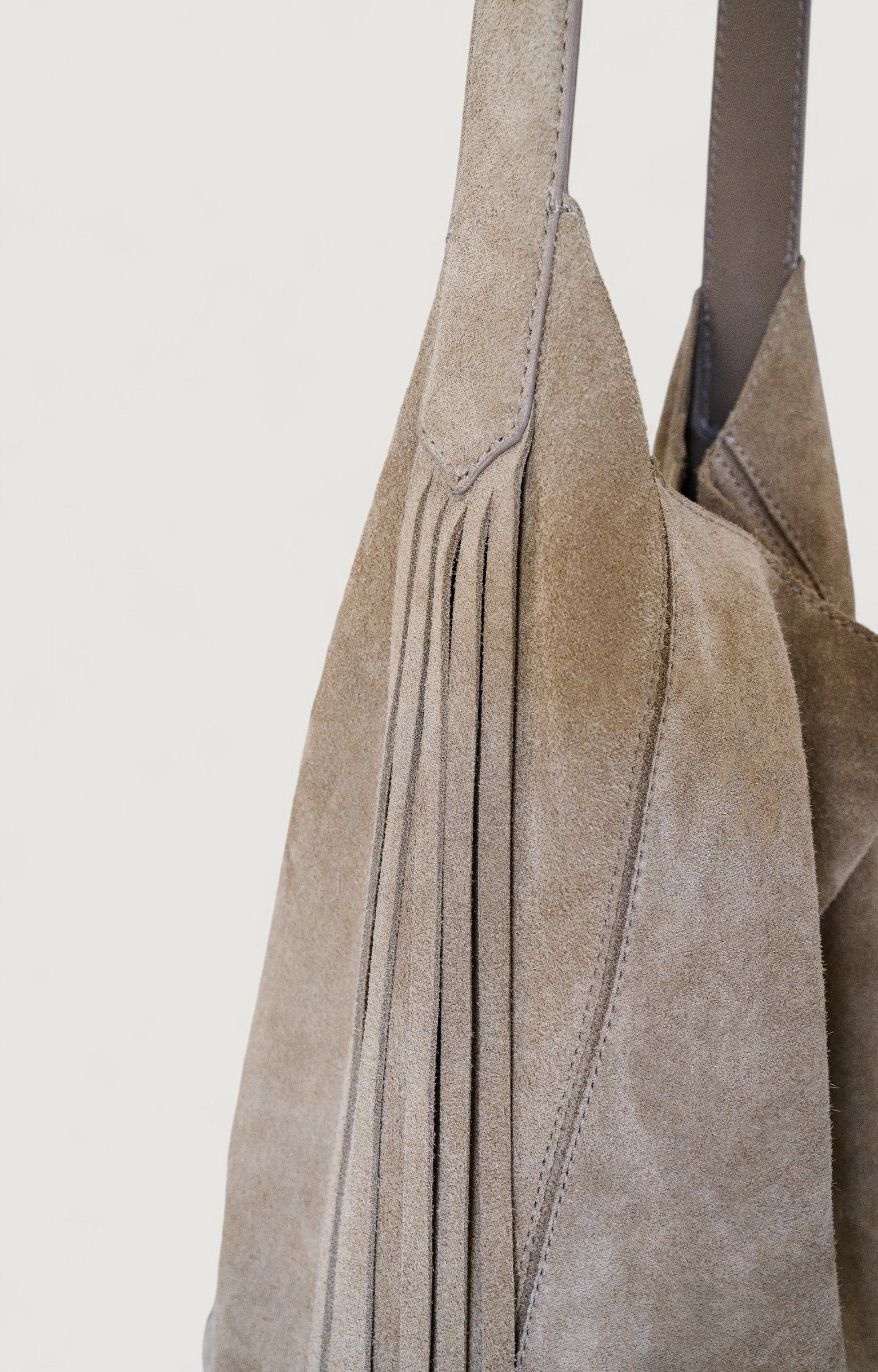 Close-up of a gray suede handbag with a plain background