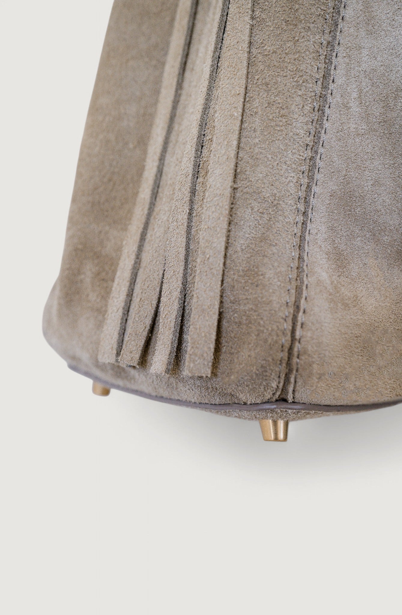 Close-up of a gray suede ottoman with pleated design on a white background