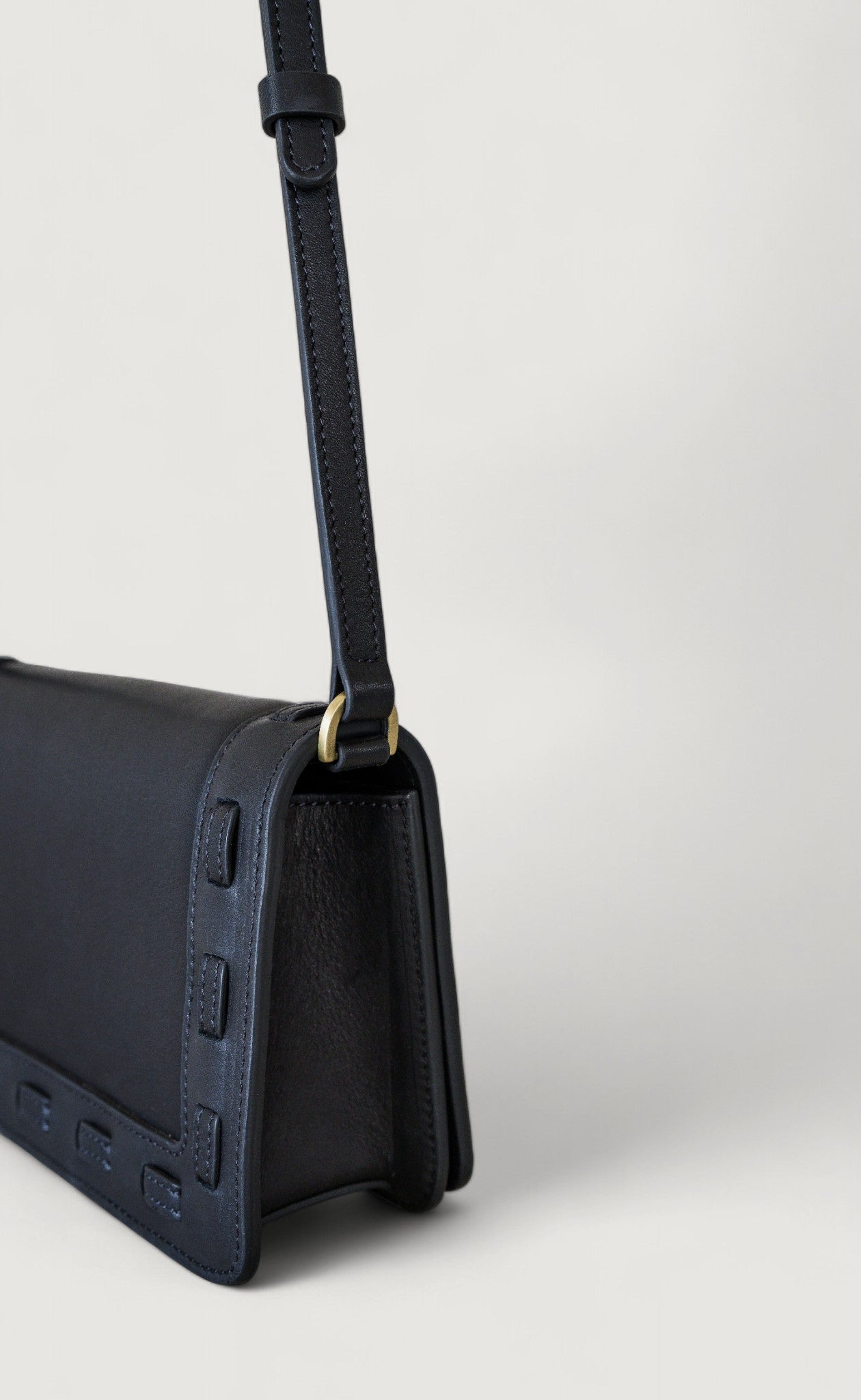 Navy blue handbag with a strap on a light gray background