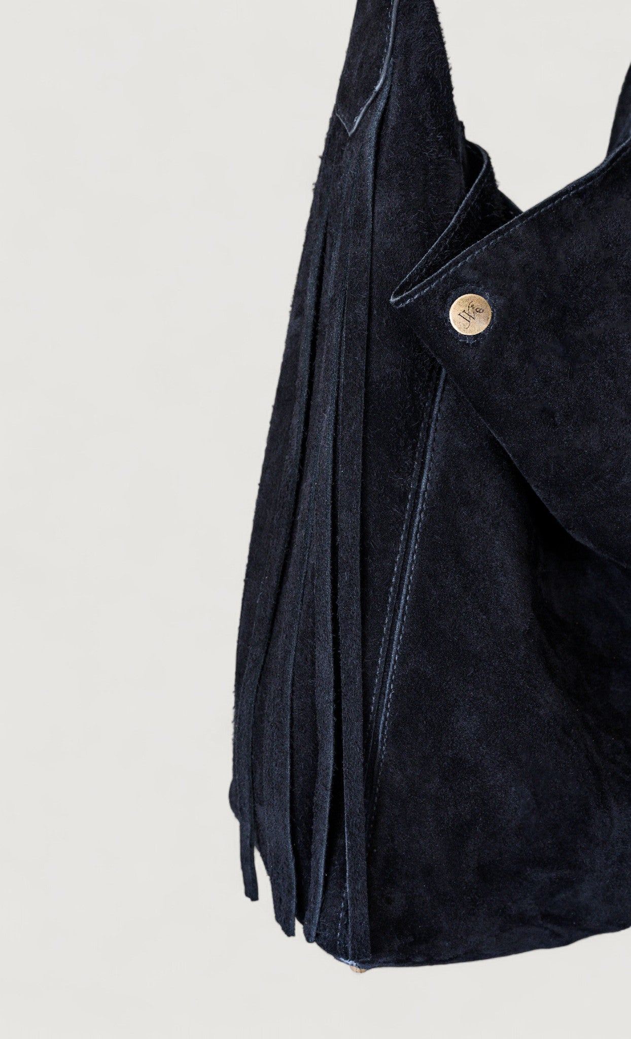 Dark blue suede bag with a brass button on a light gray background