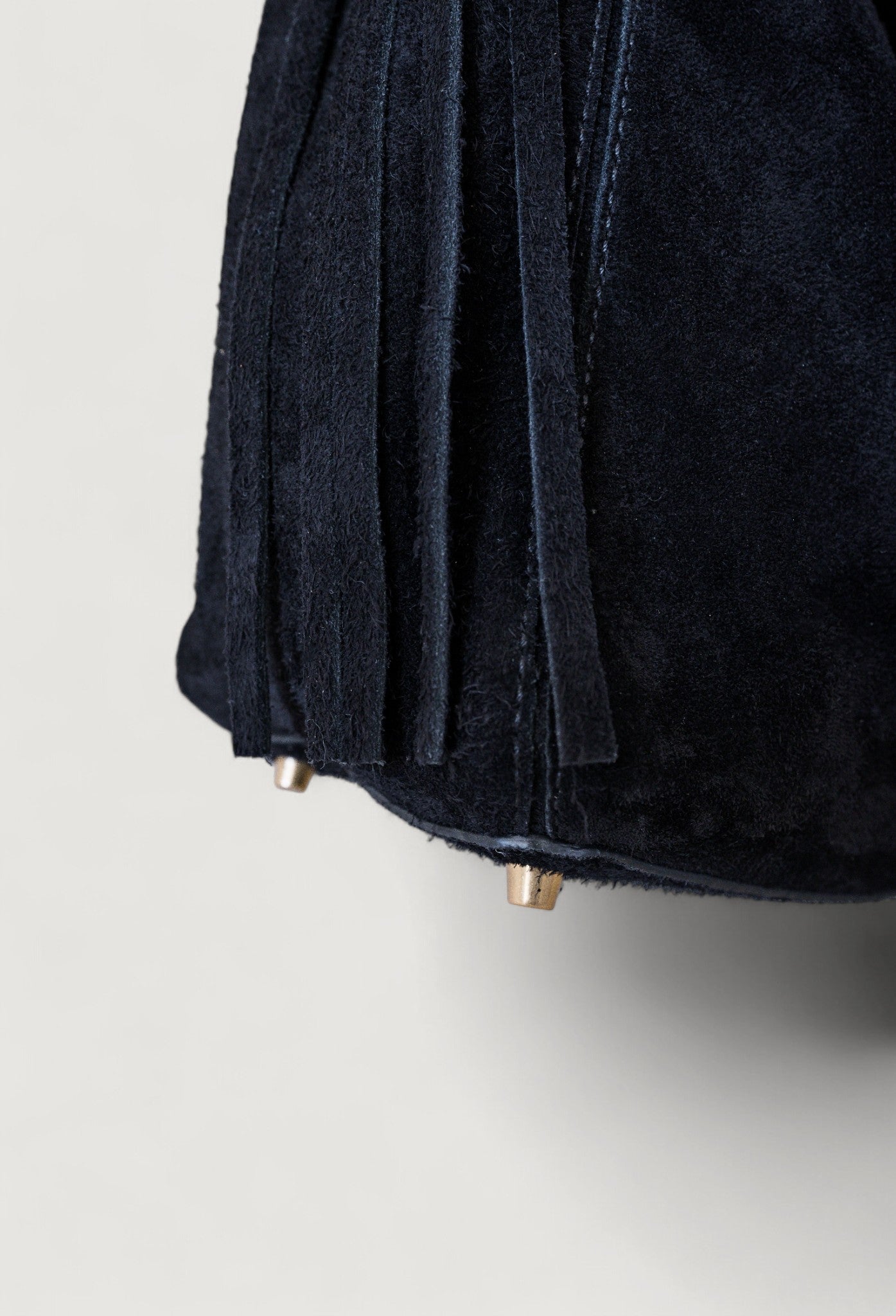 Close-up of a black suede bag on a light gray background