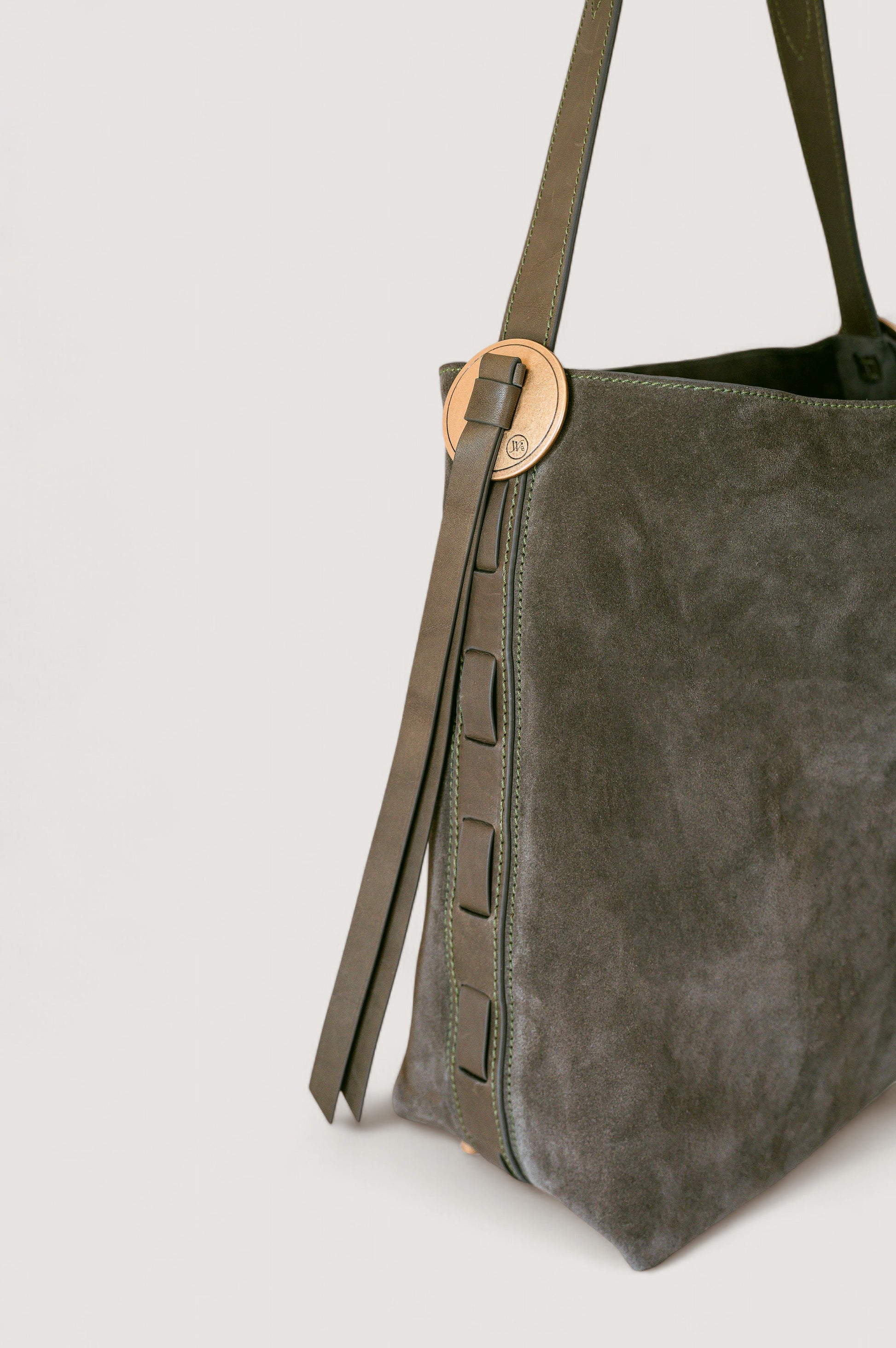 Olive suede handbag with a strap on a light gray background