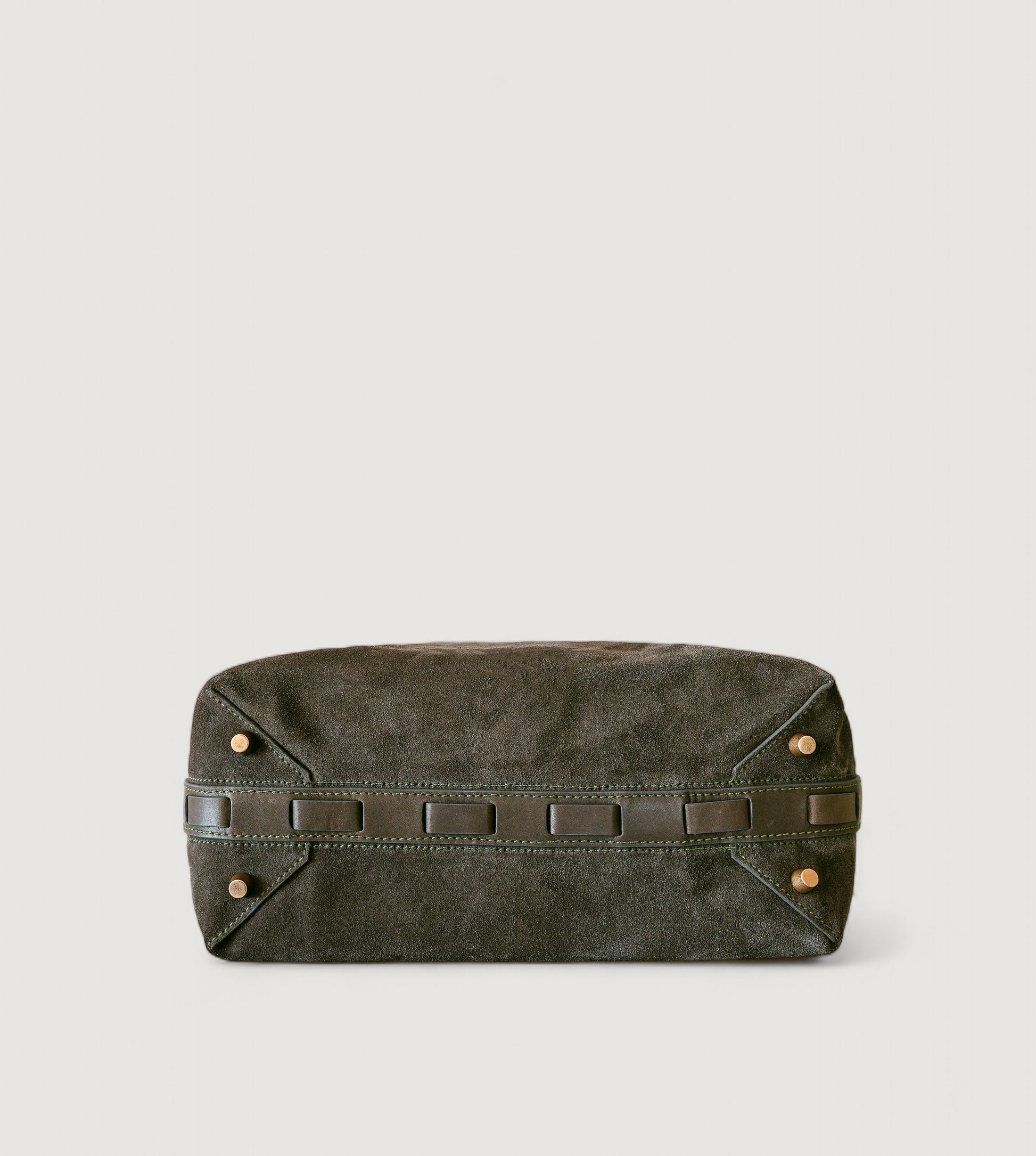 Bottom view of an olive color leather bag with brass feet on a light gray background