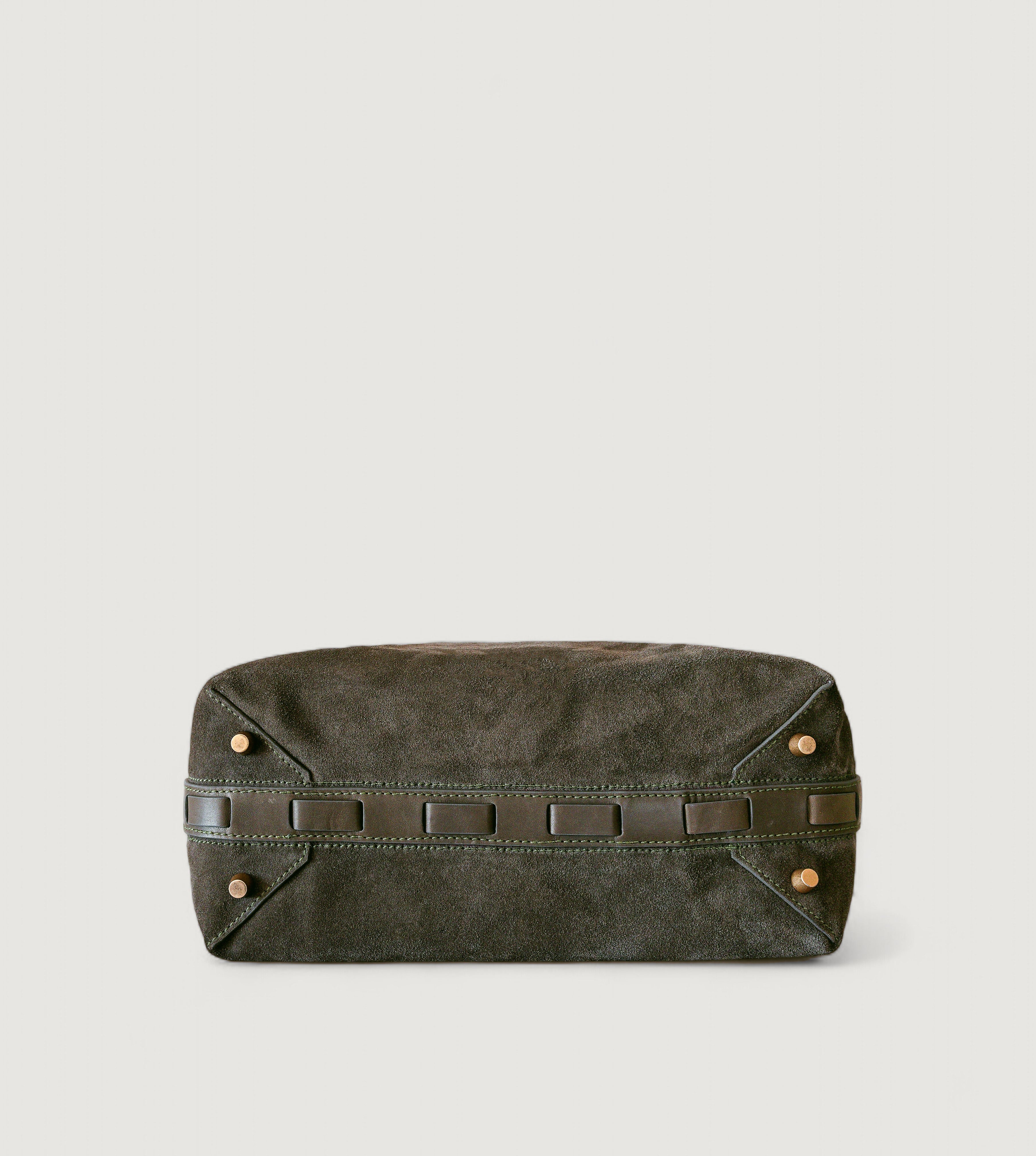 Bottom view of an olive color leather bag with brass feet on a light gray background