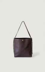 Dark brown leather handbag with a strap on a light gray background