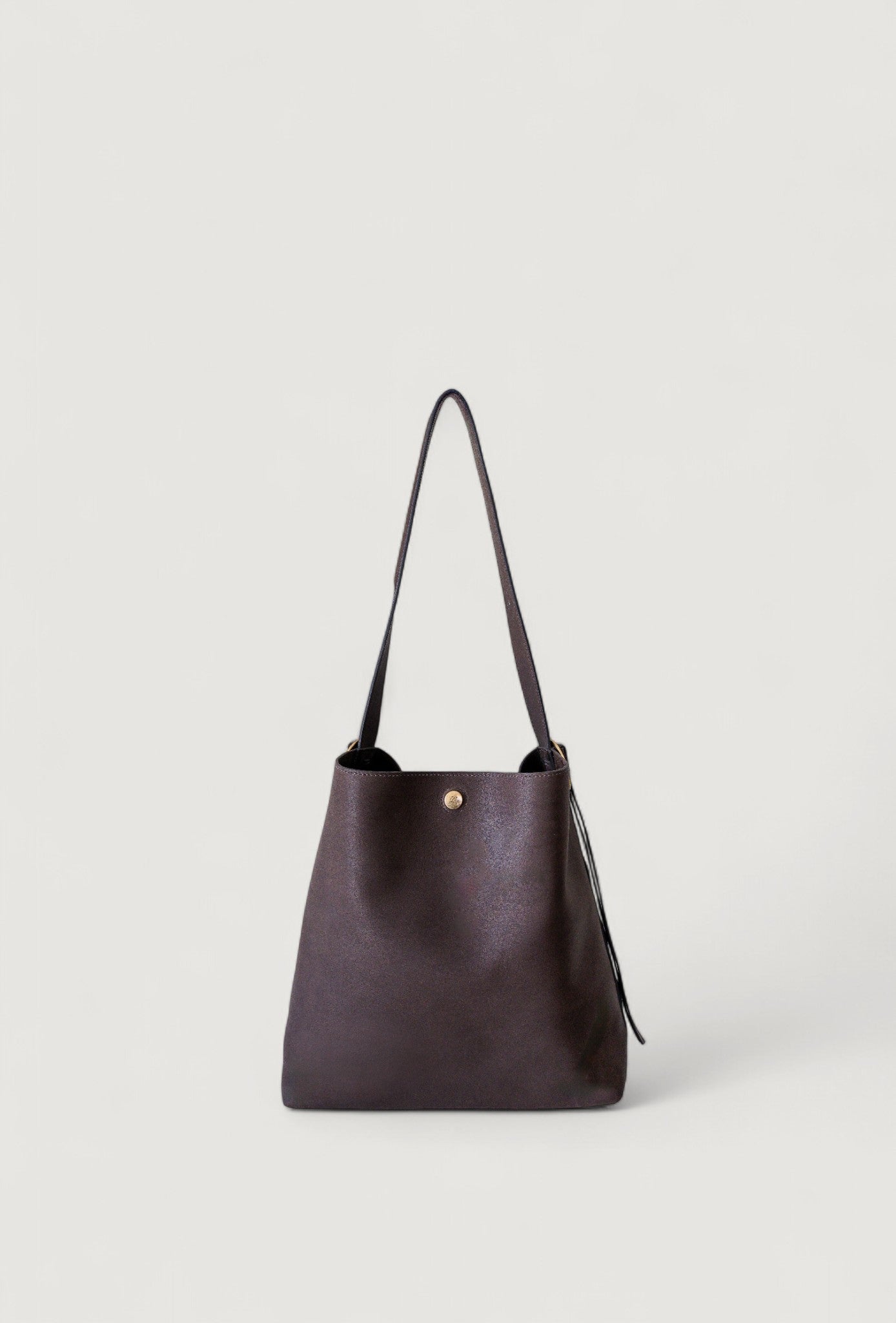 Brown leather handbag with a brass clasp on a light gray background