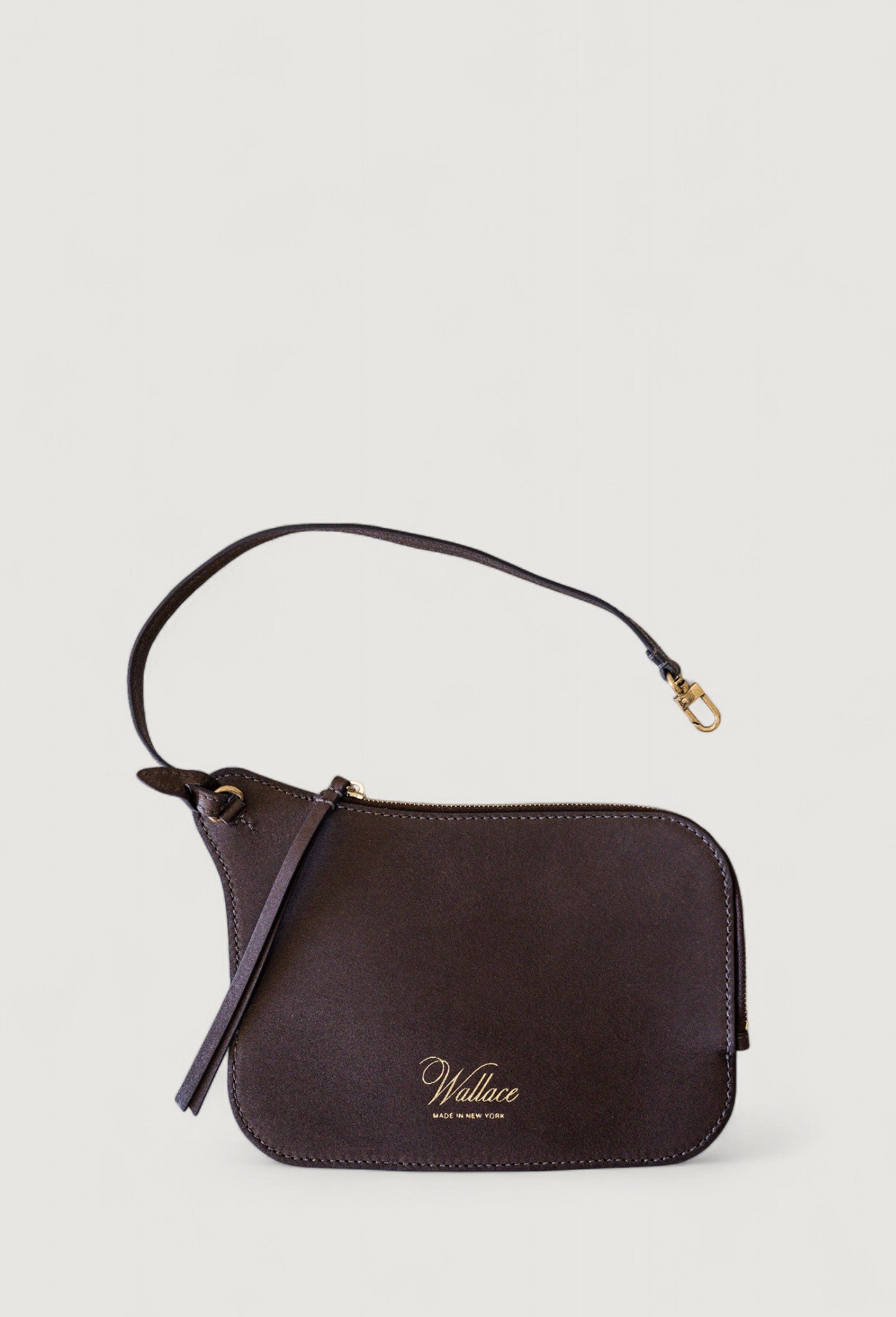 Brown leather handbag with a strap on a light gray background