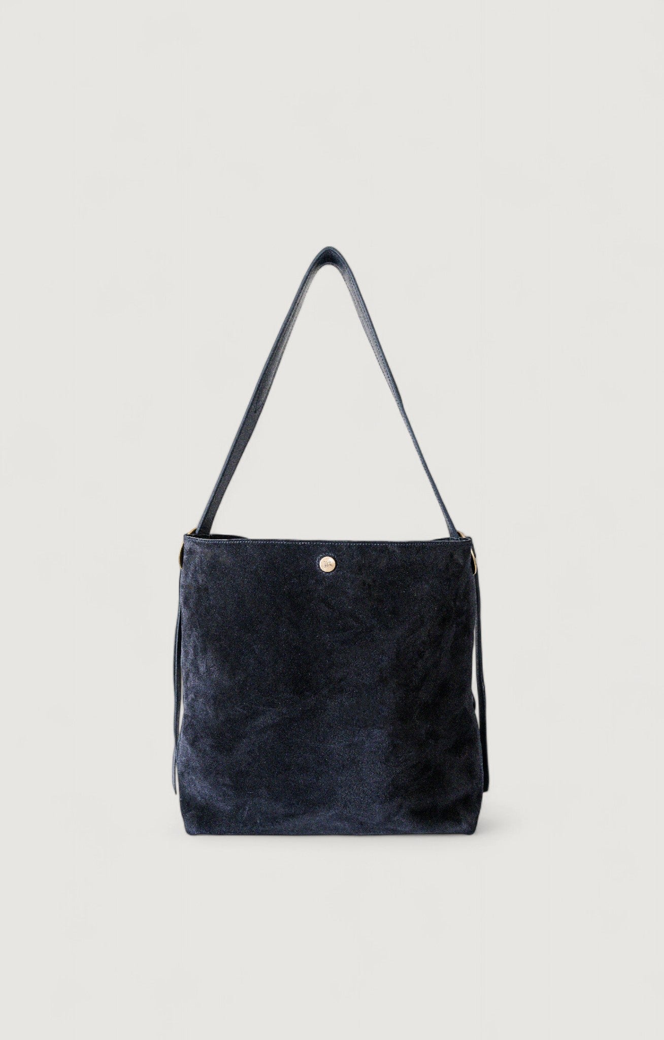Black suede handbag with a strap on a light gray background