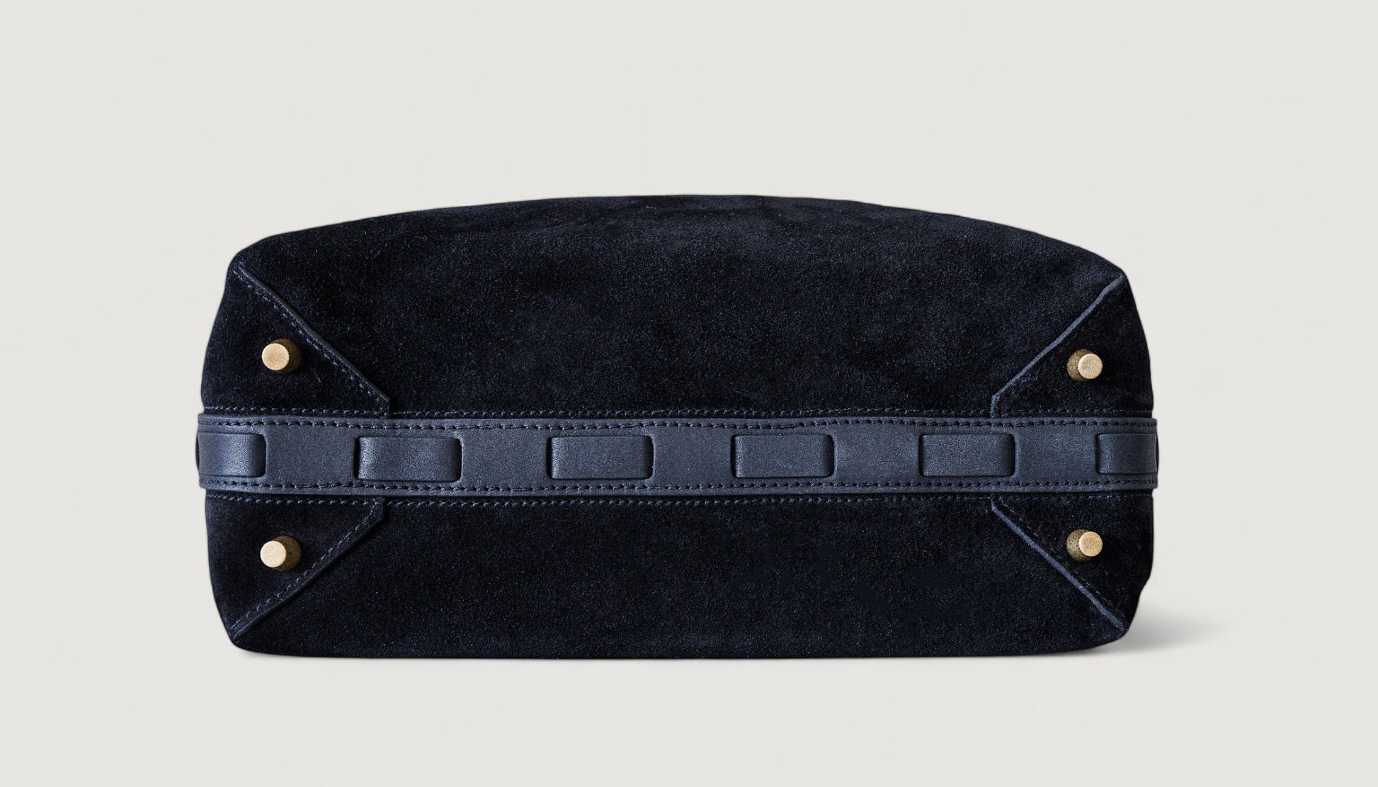 Black leather bag with brass feet on a light gray background