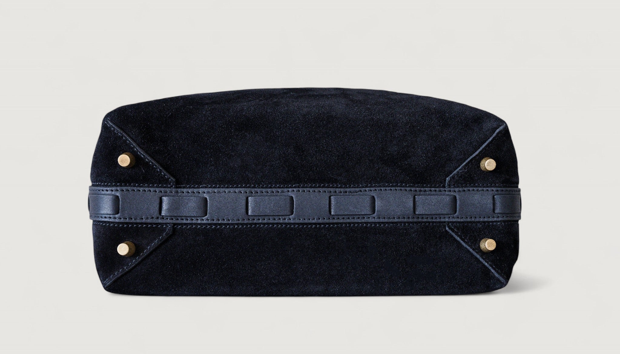 Black leather bag with brass feet on a light gray background