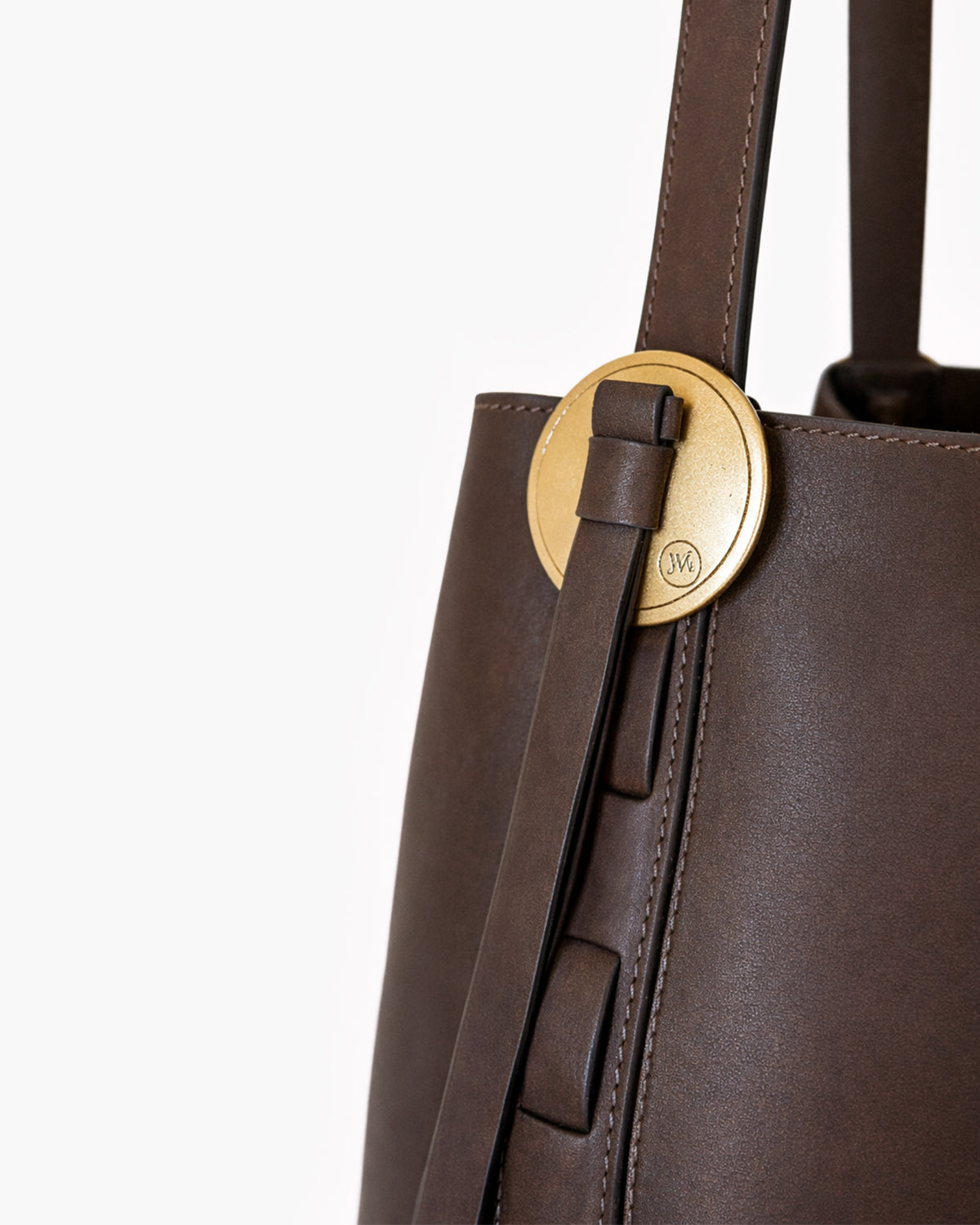 Brown leather tote bag with a gold circular clasp on a white background