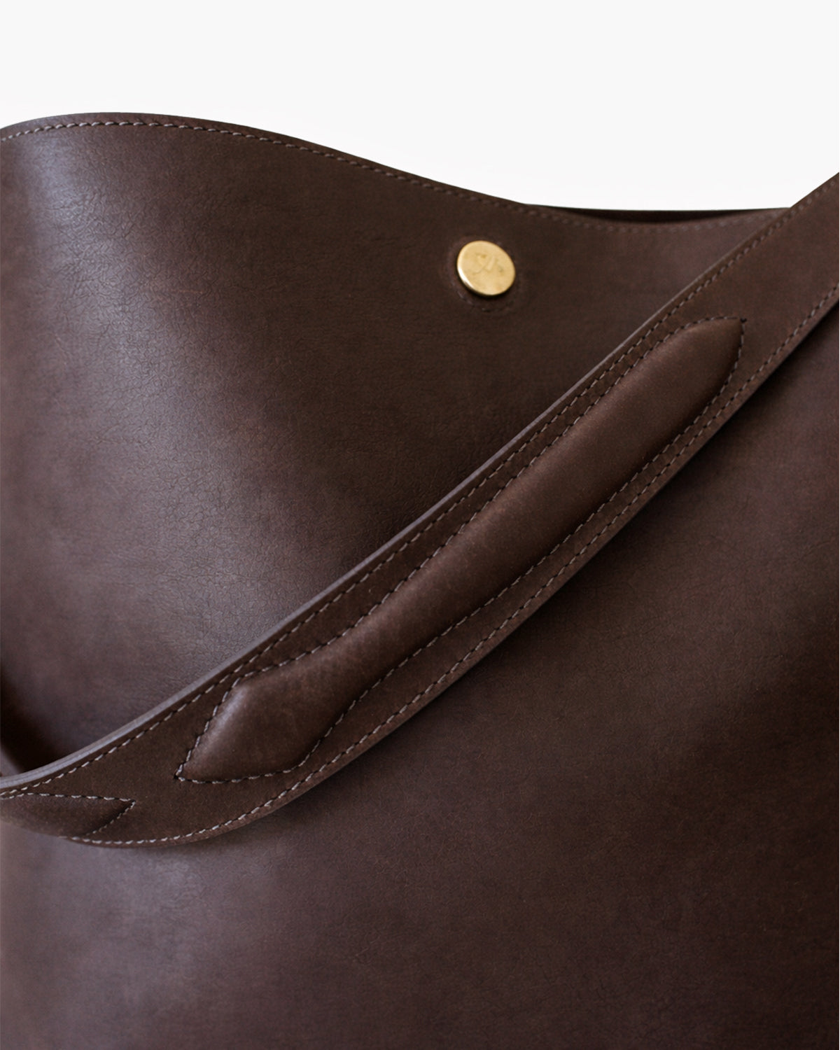 Close-up of a brown leather bag with a gold button on a white background