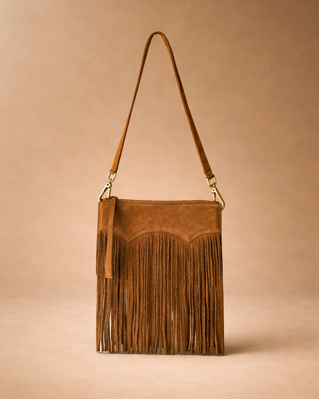 Brown suede handbag with fringe details on a beige background